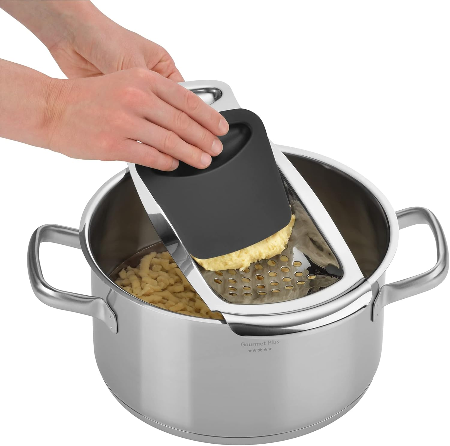 Ręce używają tarki do Spätzle do tarcia ciasta do garnka z wodą.