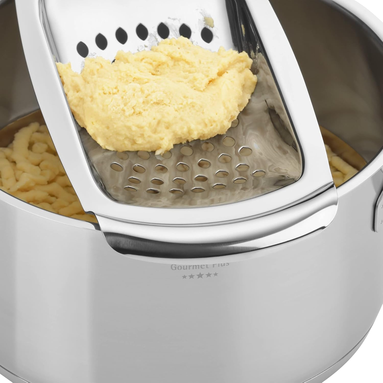 Ciasto na makaron jest przeciskane przez tarkę do garnka.