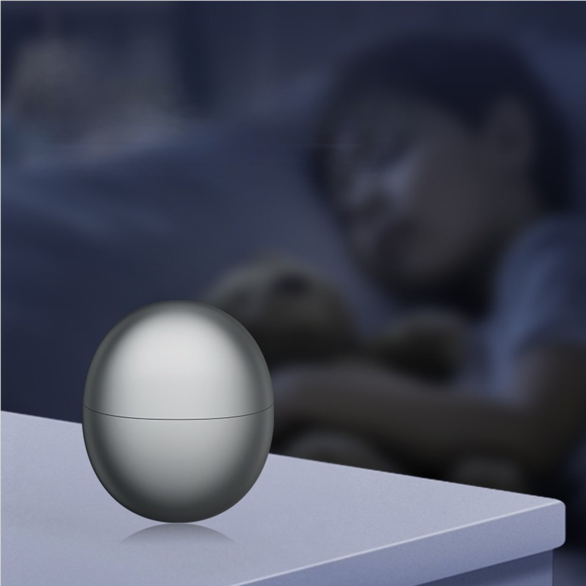 Srebrna kula na stoliku nocnym obok śpiącego dziecka.