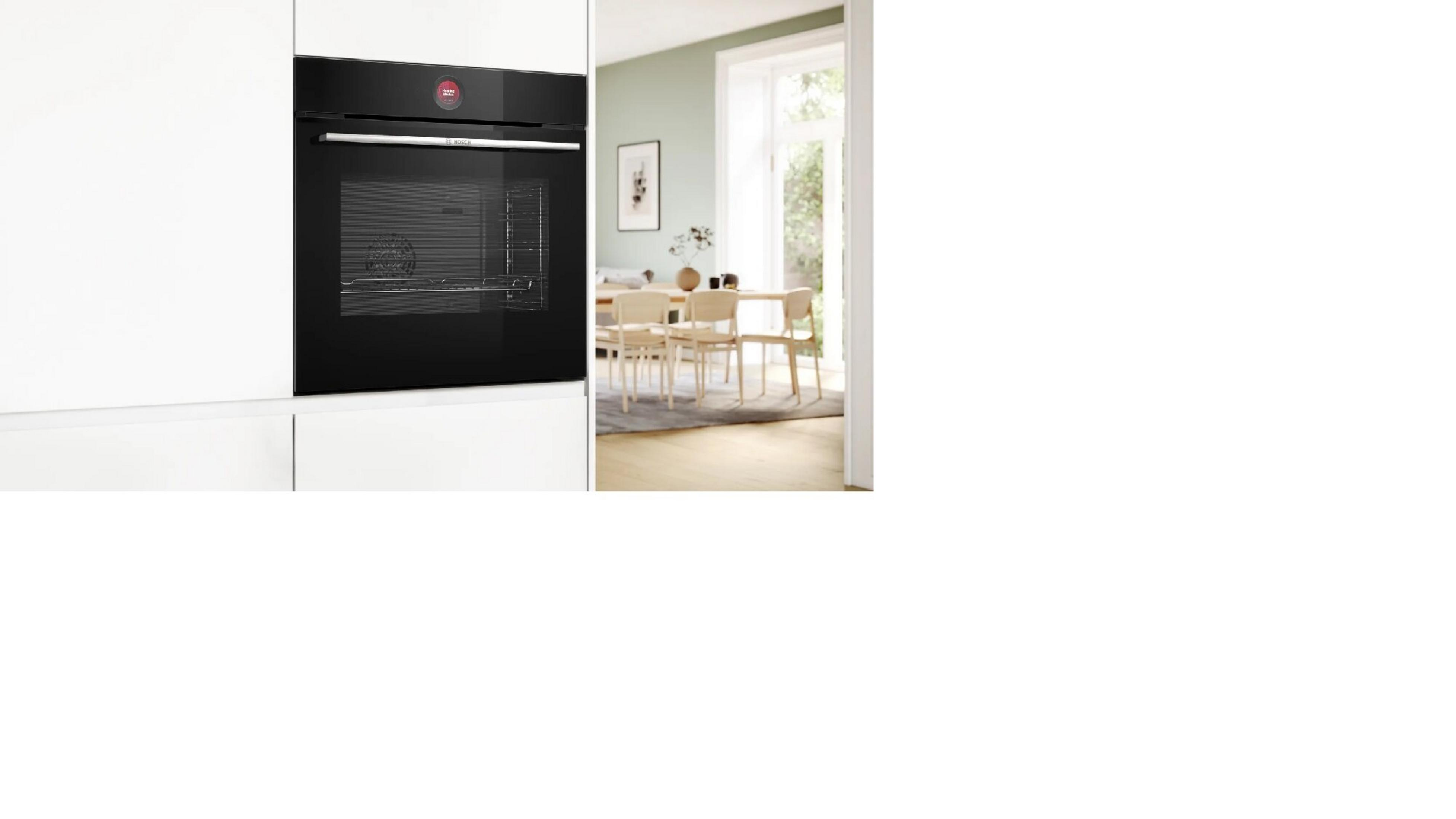 Forno da incasso nero moderno accanto a una zona pranzo con tavolo e sedie in legno.