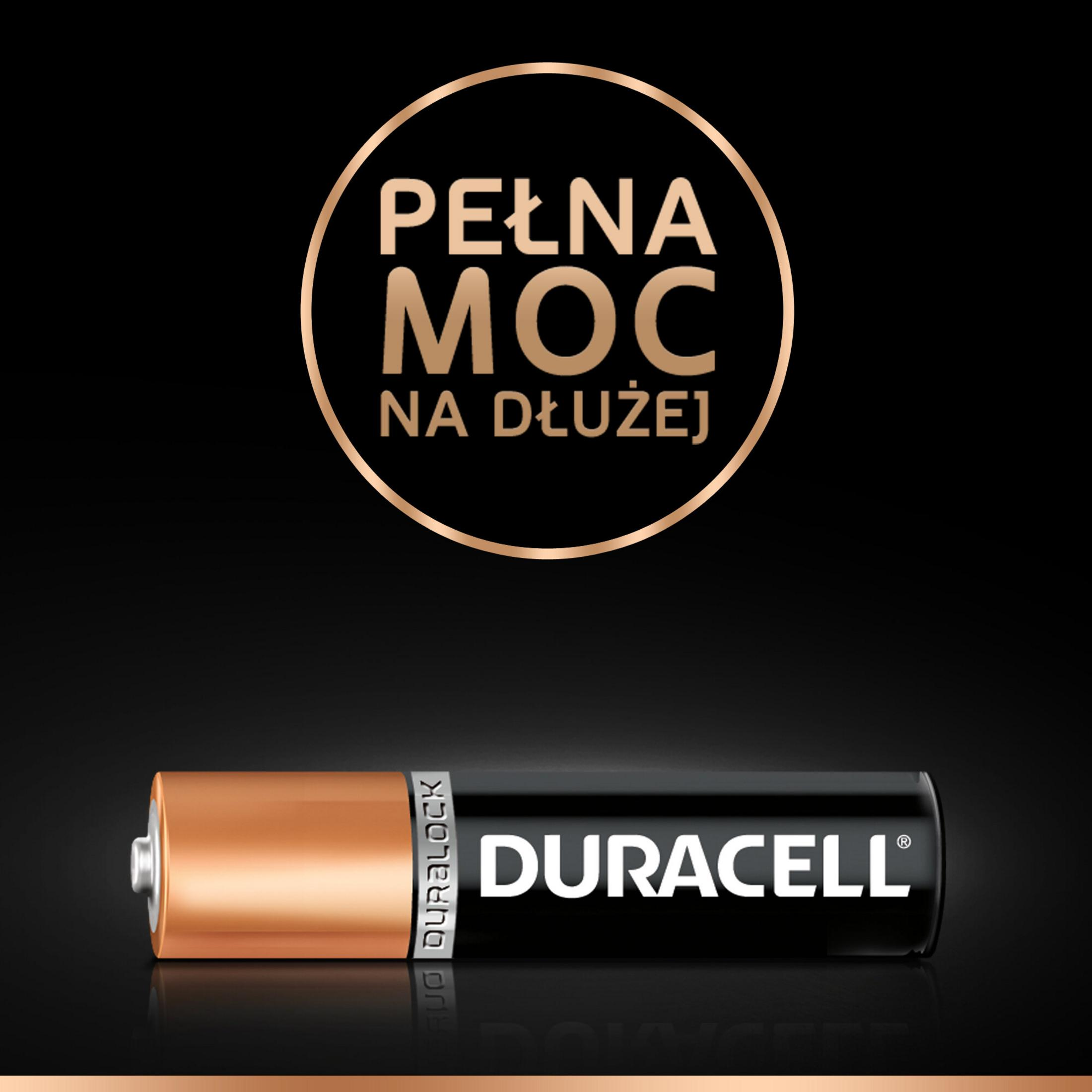 Bateria Duracell na czarnej, odbijającej światło powierzchni, z napisem "PEŁNA MOC NA DŁUŻEJ" w złotym okręgu powyżej.