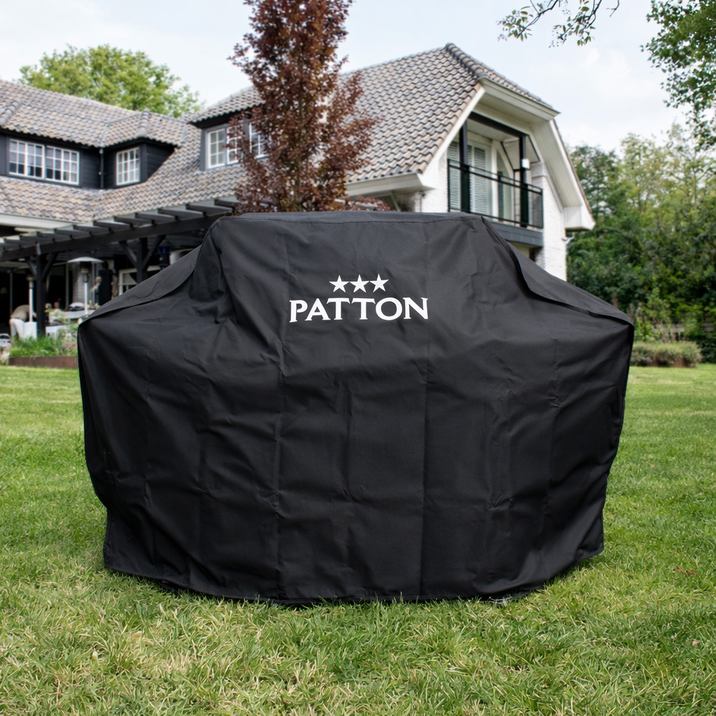 A black grill cover with the PATTON logo on a lawn in front of a house.