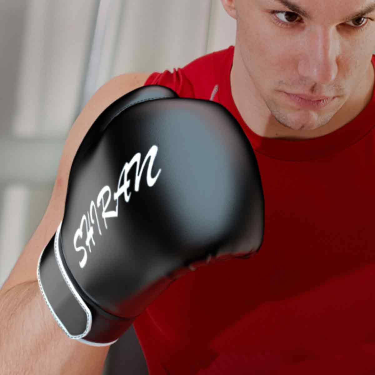 Ein Mann in einem roten Hemd trägt einen schwarzen Boxhandschuh mit weißer Schrift.