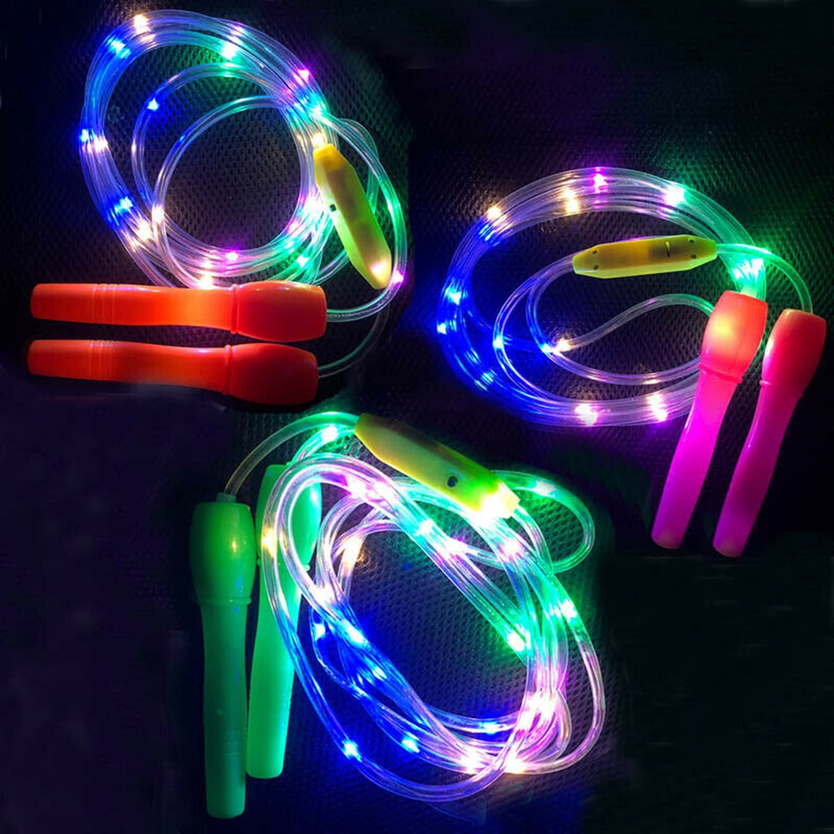 Drei leuchtende Springseile mit bunten LED-Lichtern und Griffen in Grün, Orange und Pink.