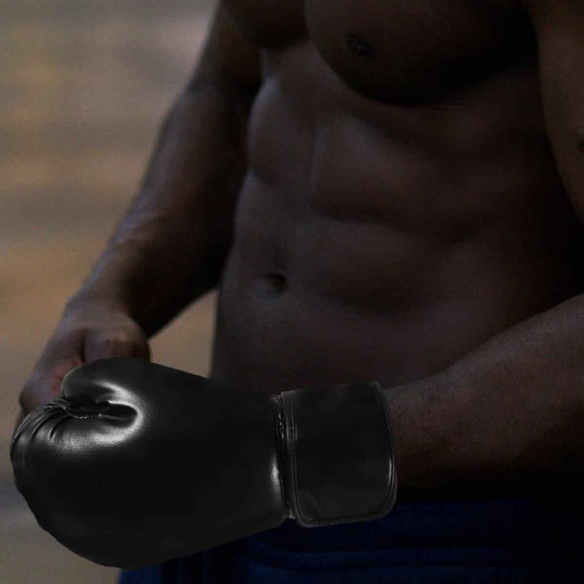 Ein Mann mit schwarzen Boxhandschuhen und trainiertem Körper.