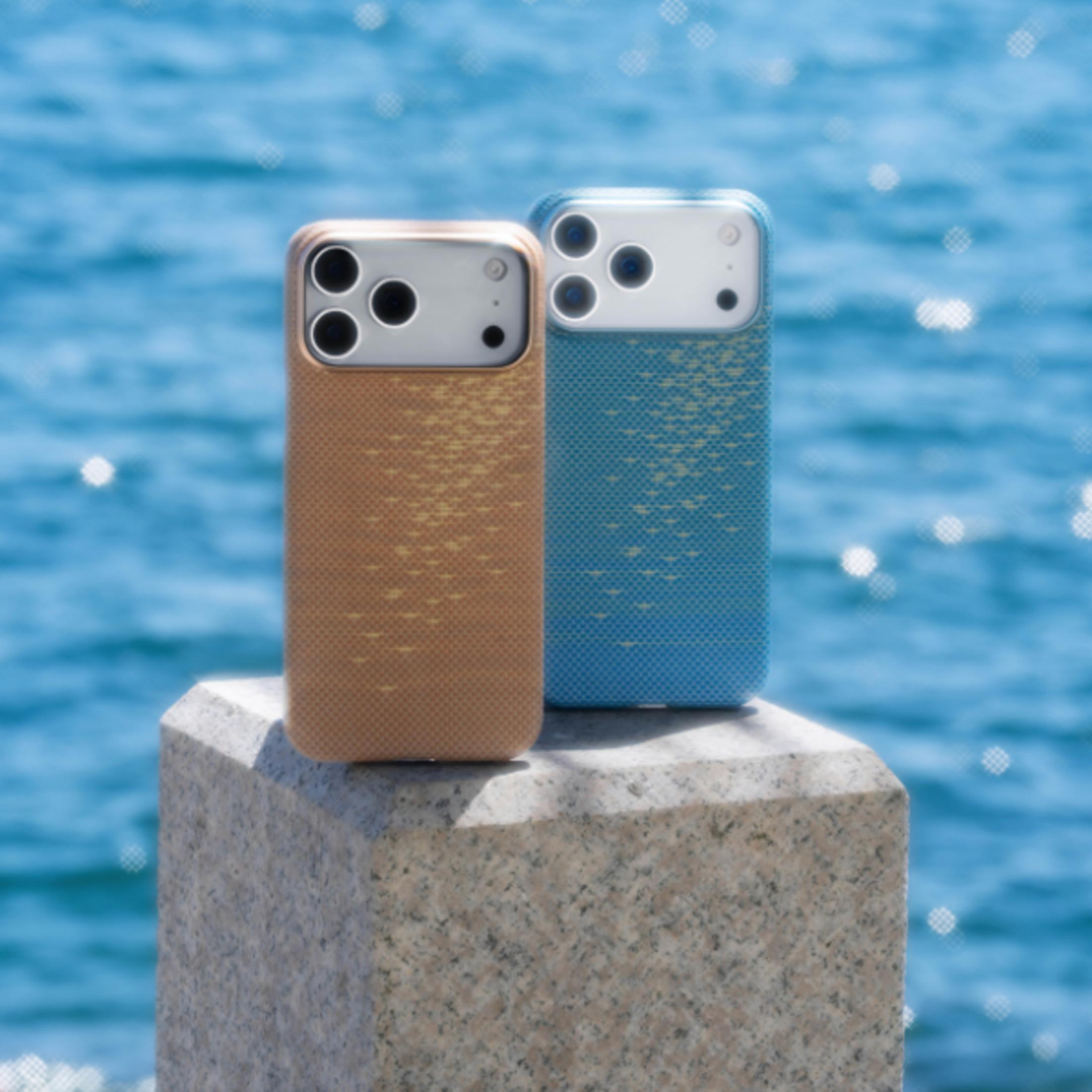 Dos teléfonos, uno dorado y otro azul, sobre un bloque de piedra con agua azul.