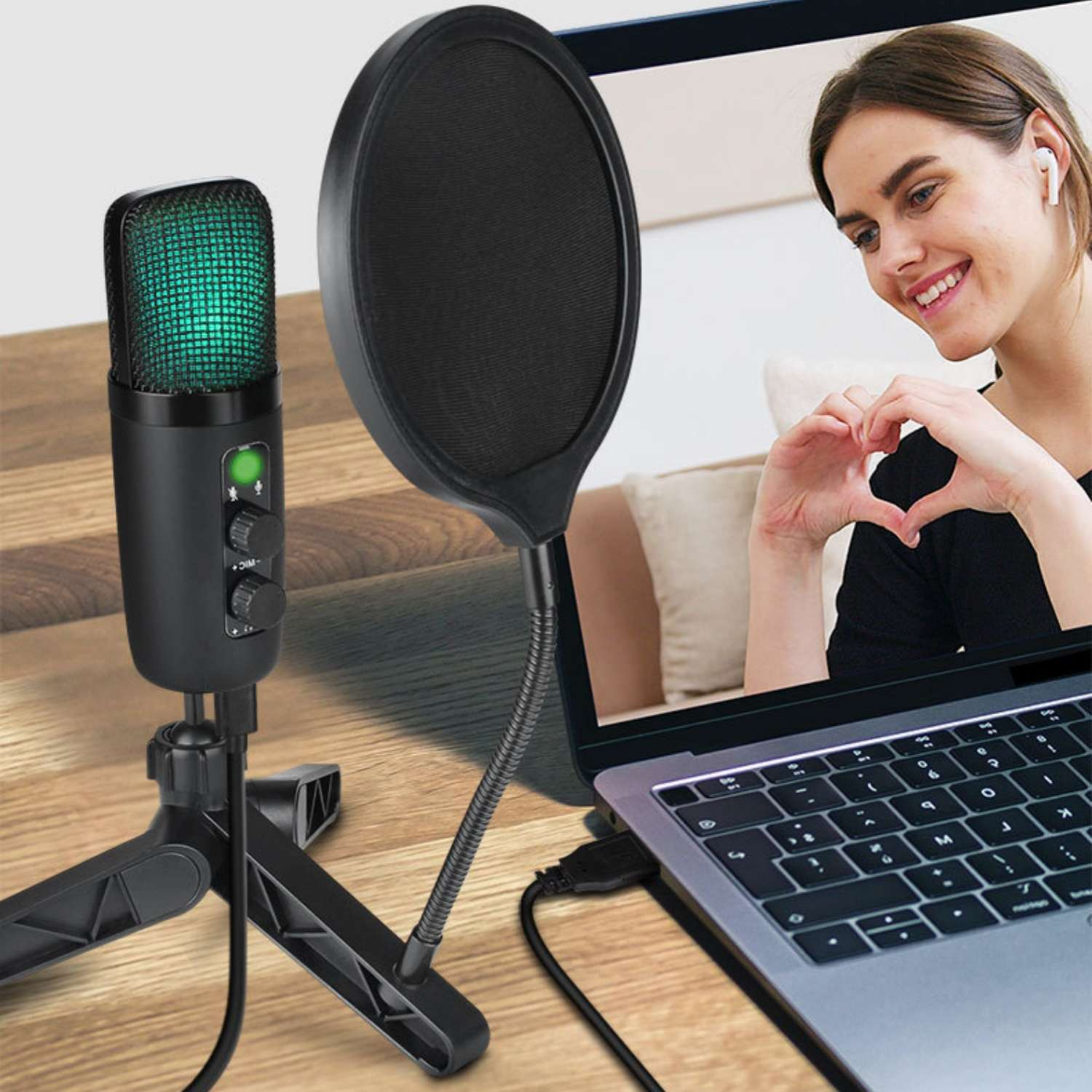 Ein schwarzes Mikrofon mit grünem Licht und einem Popfilter steht neben einem Laptop, der eine lächelnde Frau zeigt.