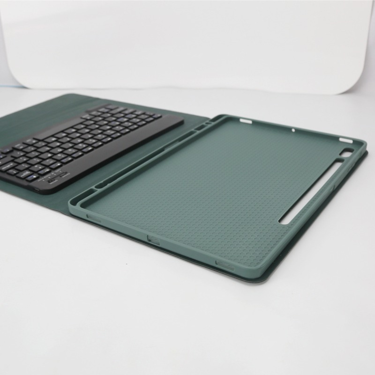 Una tastiera nera poggia su una custodia verde per tablet.
