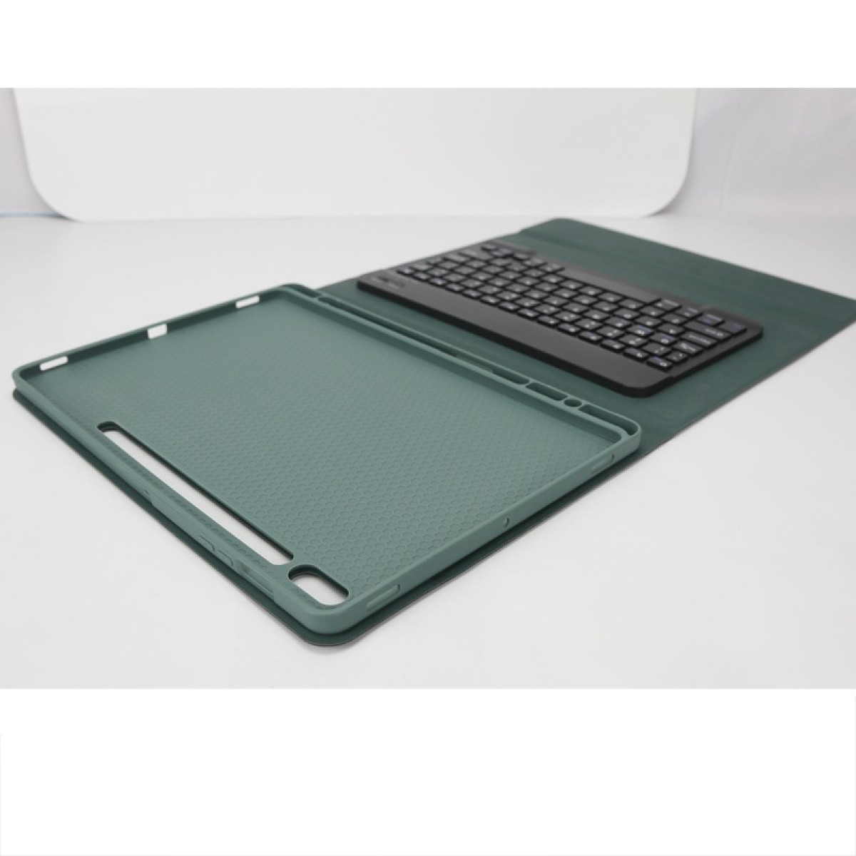Custodia verde per tablet e tastiera nera su sfondo scuro.