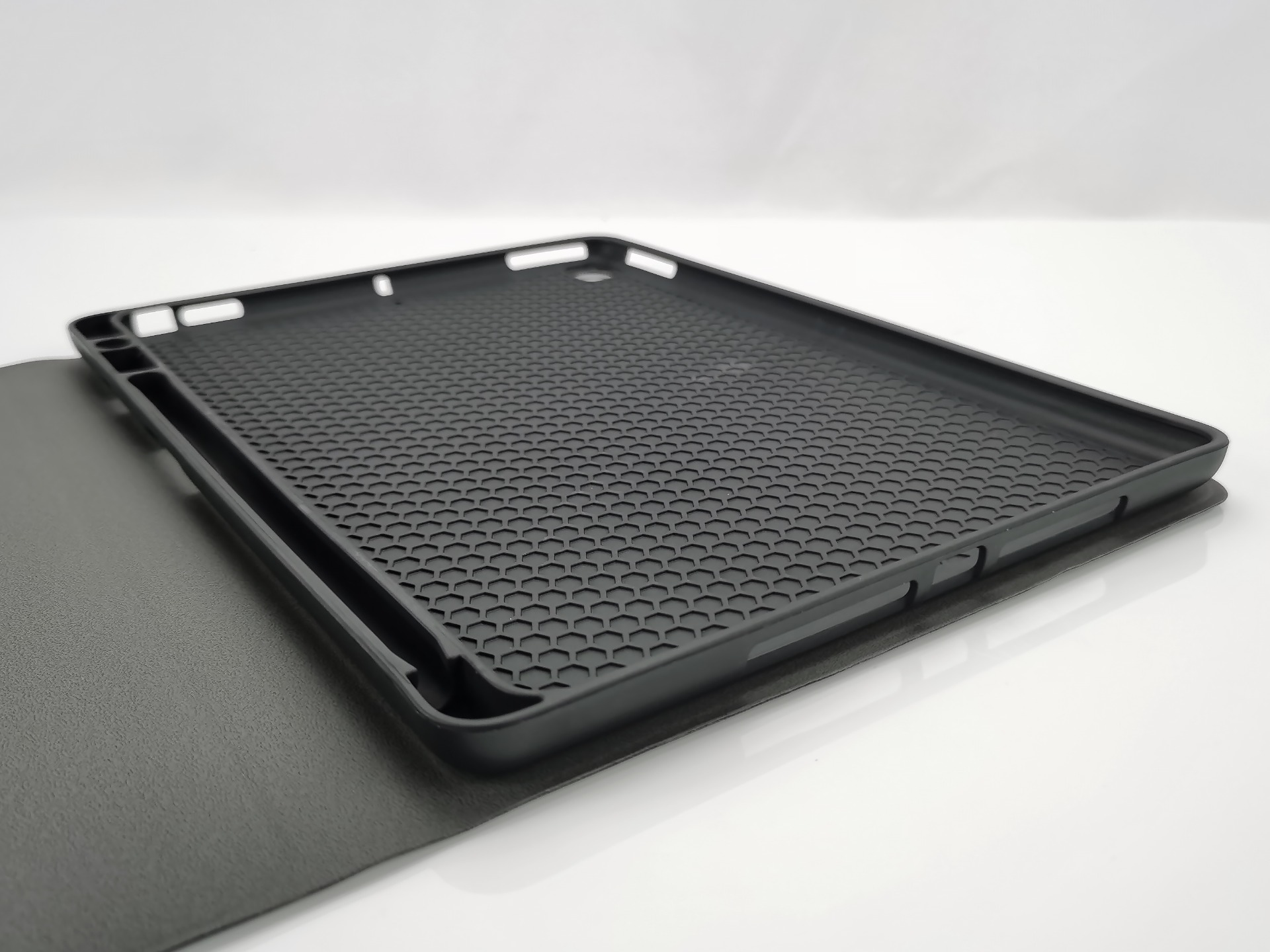 Czarne etui na tablet z teksturą plastra miodu i wycięciami na białym tle.