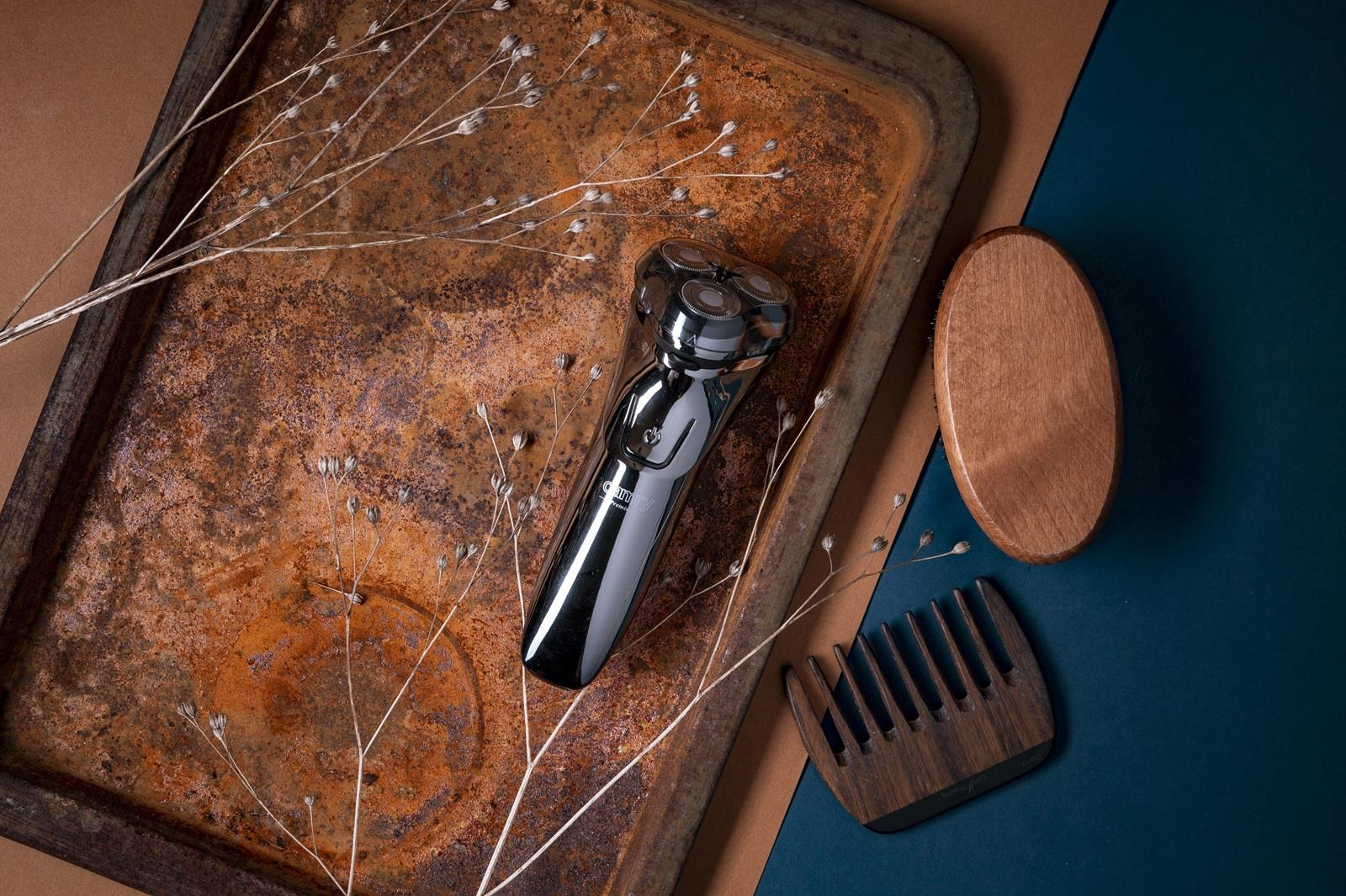 Srebrna golarka leży na zardzewiałej tacy obok drewnianego grzebienia i szczotki.