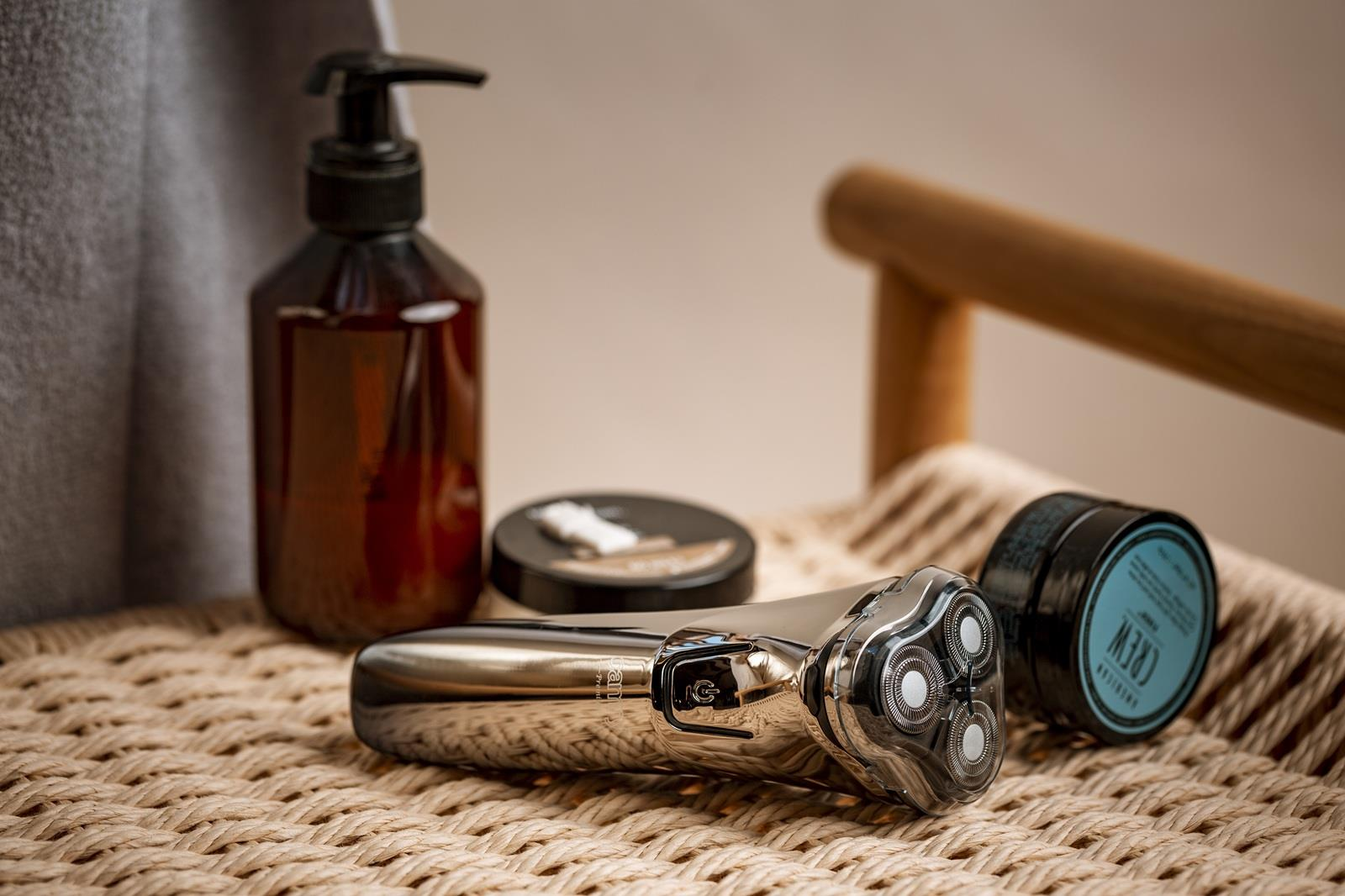 Golarka, butelka z mydłem i dwa pojemniki na plecionej powierzchni.