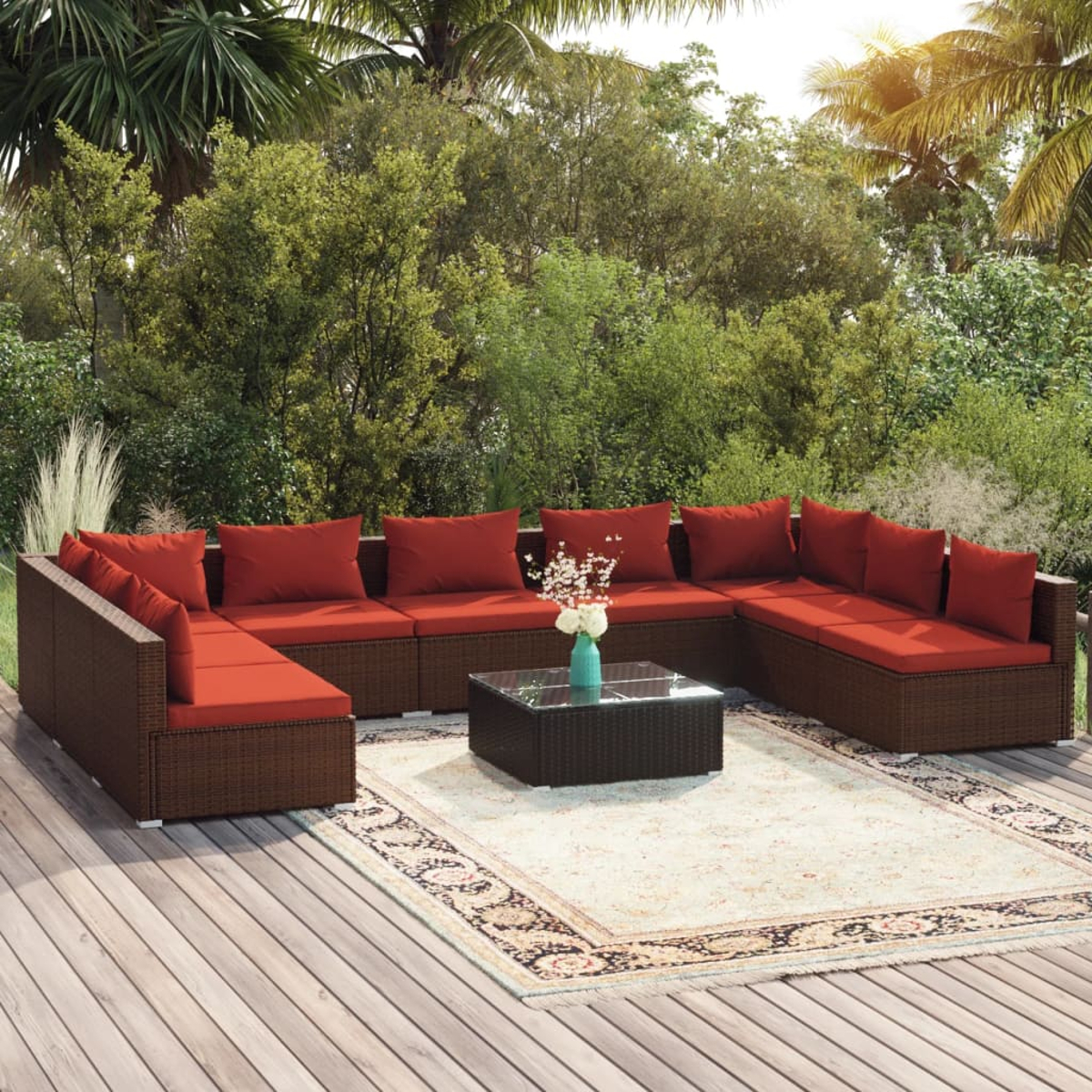 Ein braunes Rattan-Sofa mit roten Kissen und ein Couchtisch auf einer Holzterrasse.