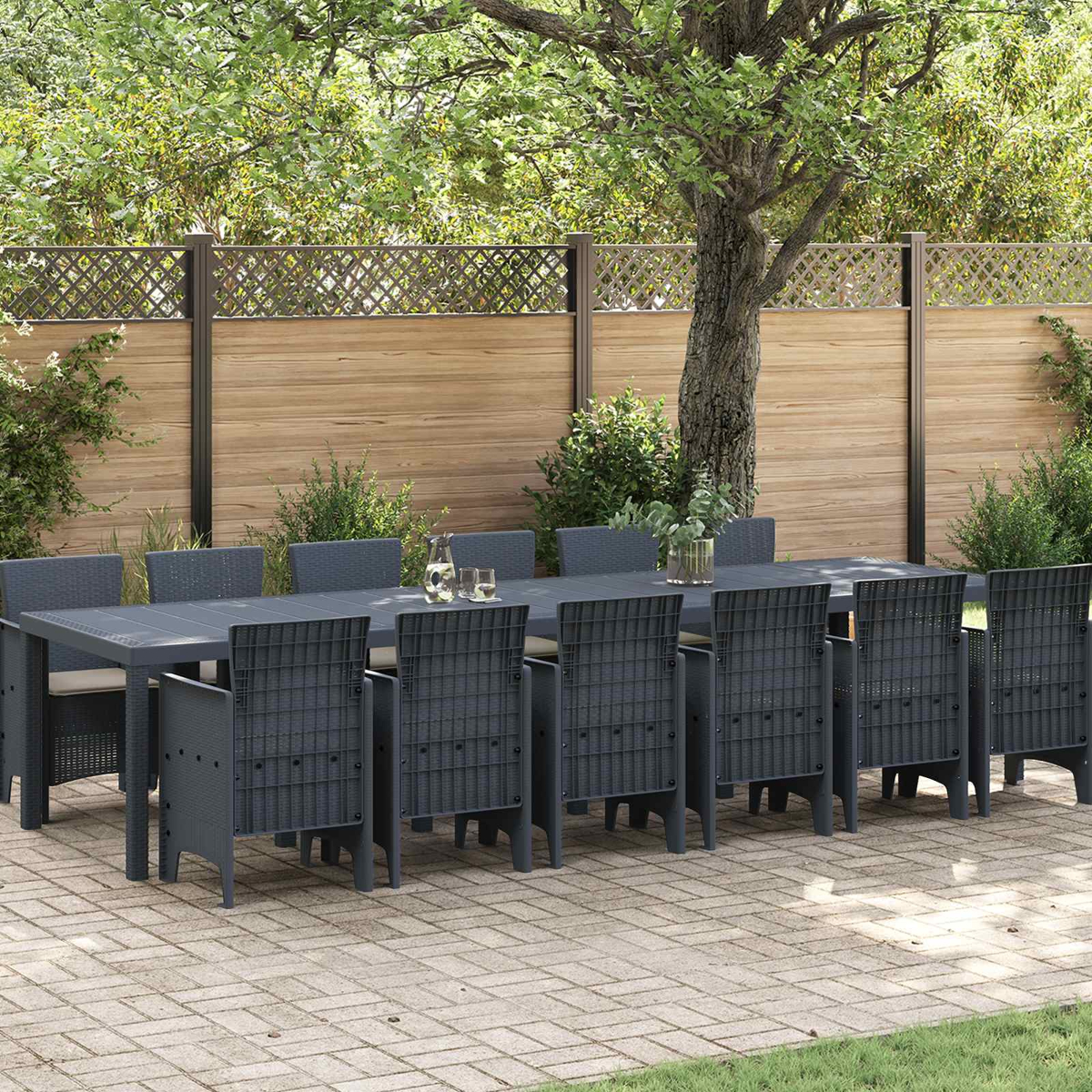 Dunkelgraue Gartenmöbelgarnitur mit Tisch und Stühlen auf einer Kopfsteinpflasterterrasse.
