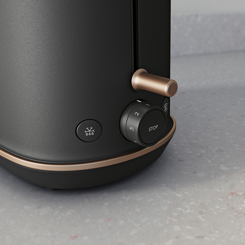 Czarny toster z miedzianymi akcentami i pokrętłem regulacji stopnia zrumienienia.