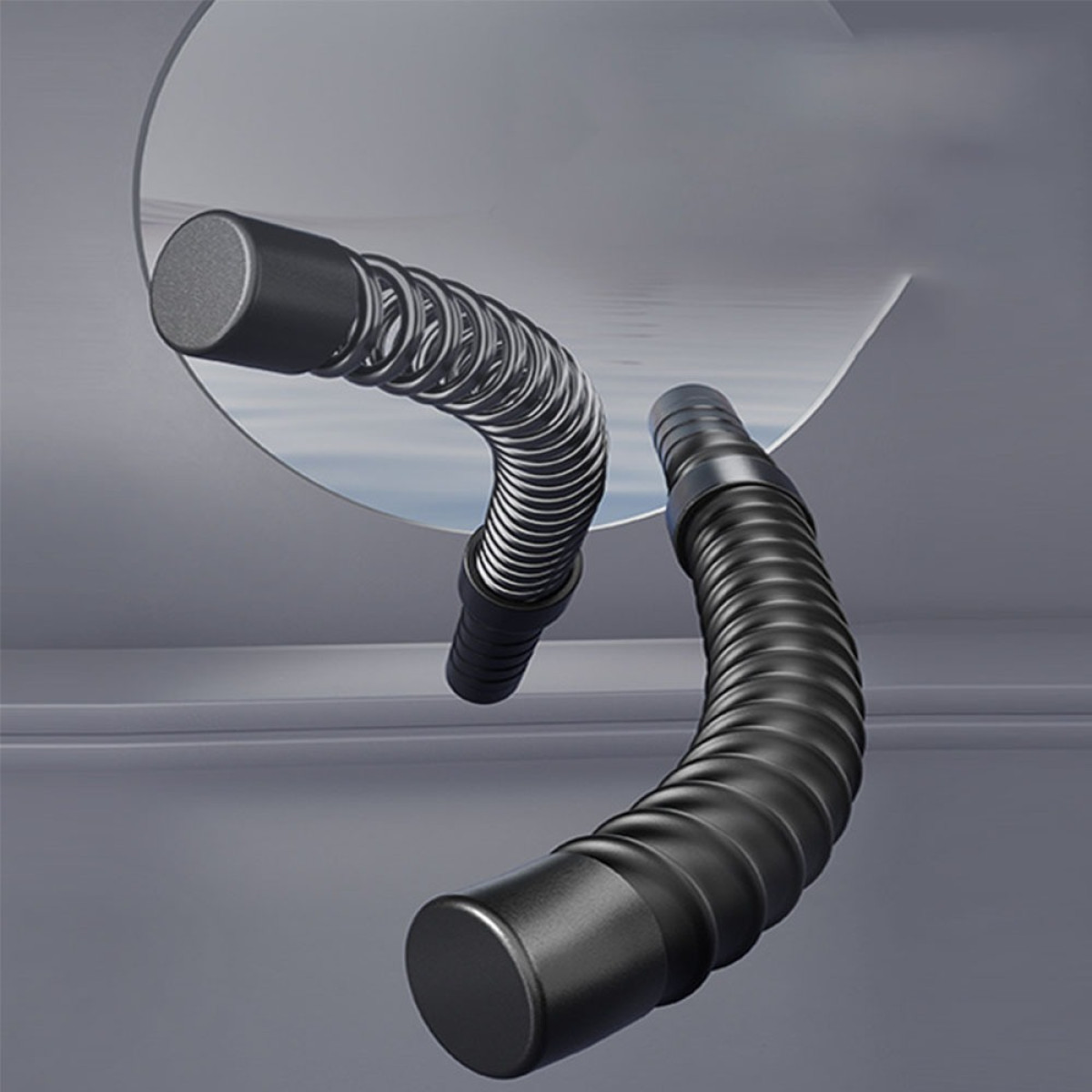 Dwa czarne elastyczne węże z metalowymi sprężynami, wyginające się.