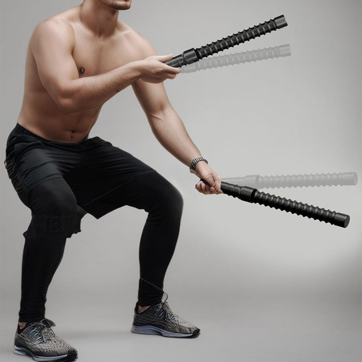 Mężczyzna bez koszulki kuca, trzymając w dłoniach dwie czarne pałki.