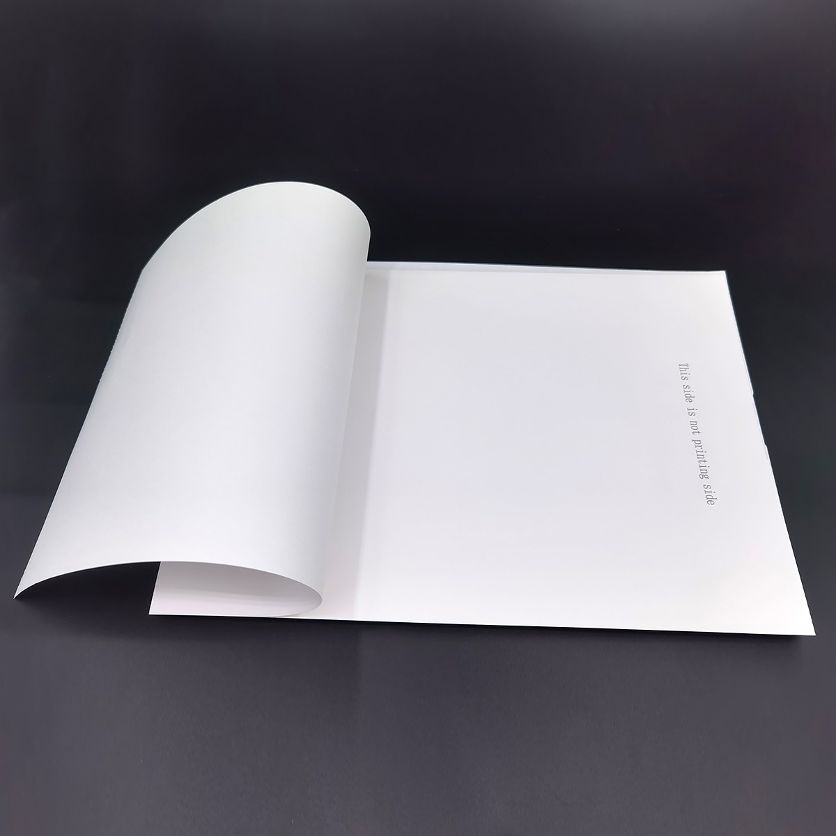 Biała kartka papieru z podwiniętym rogiem na czarnym tle.