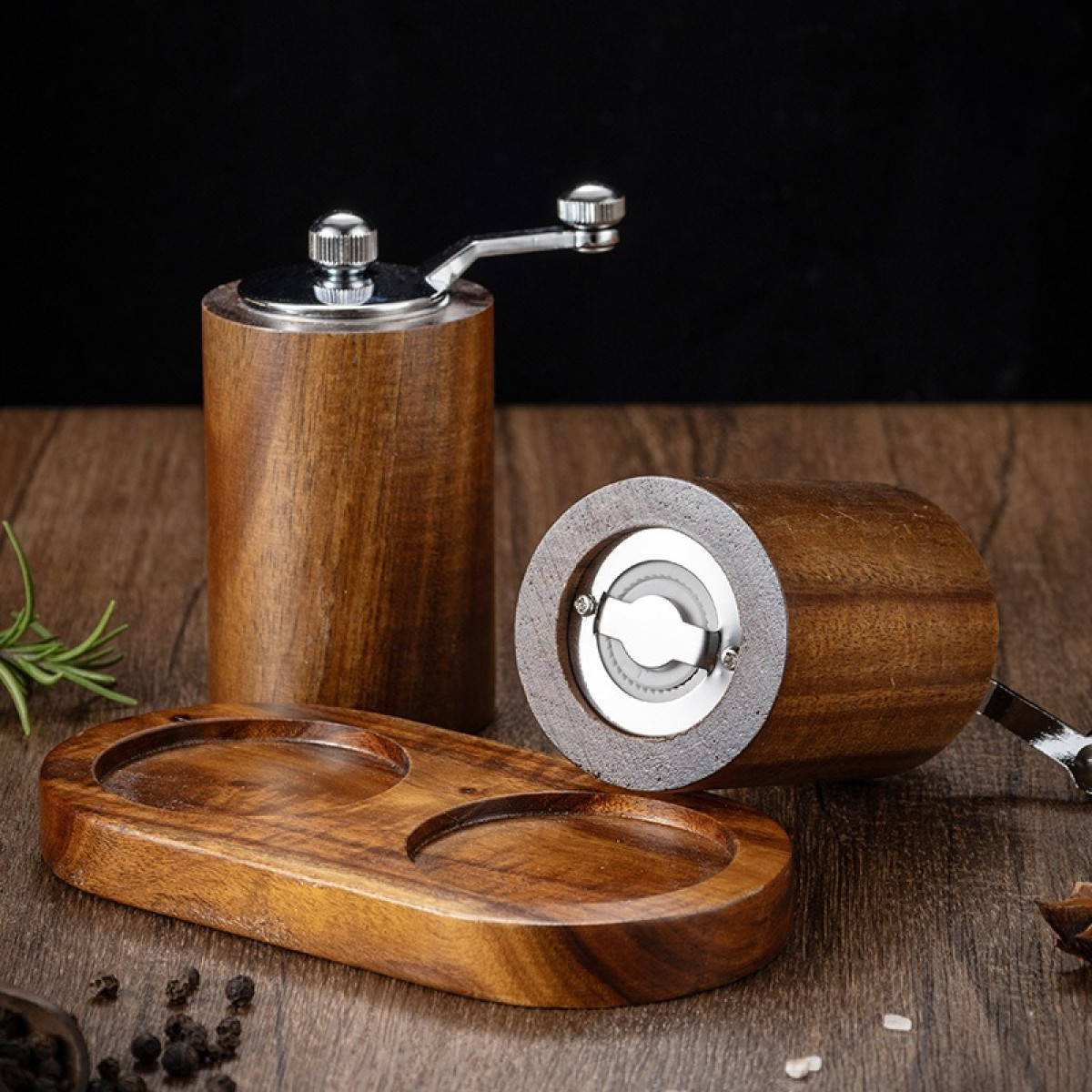 Dwa drewniane młynki do pieprzu, jeden pionowo, jeden poziomo, ze srebrnymi korbkami.