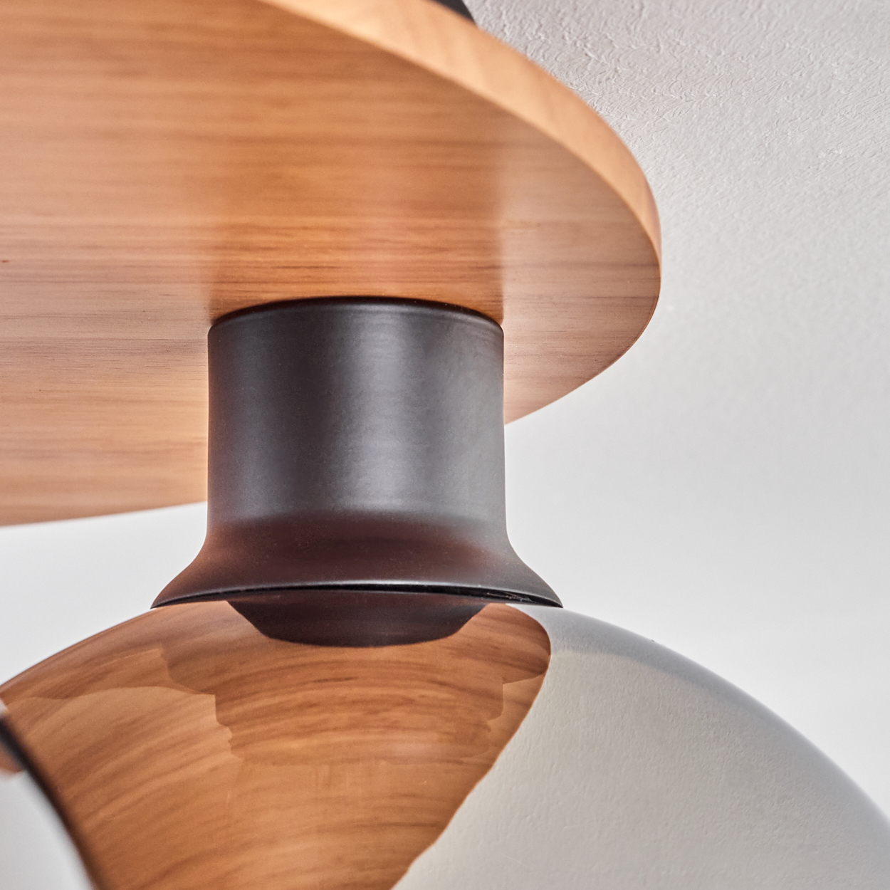 Holzplatte mit dunklem Metallzylinder und reflektierendem Lampenschirm.