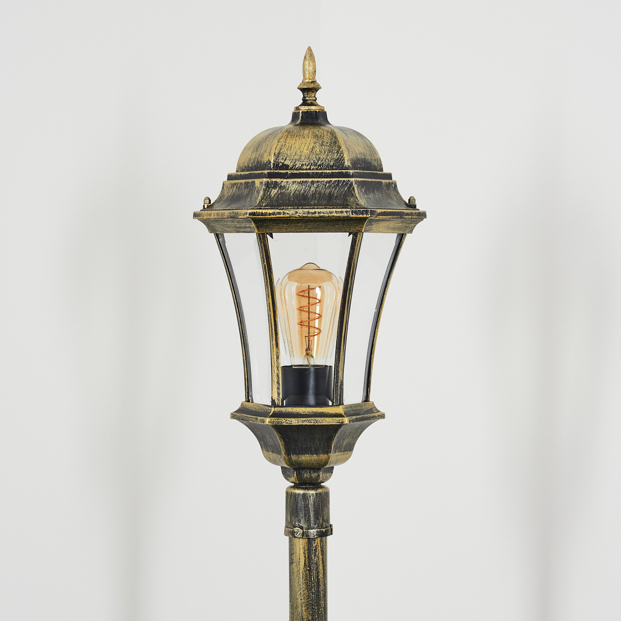 Antiker schwarzer und goldener Laternenpfahl mit einer Glühbirne.