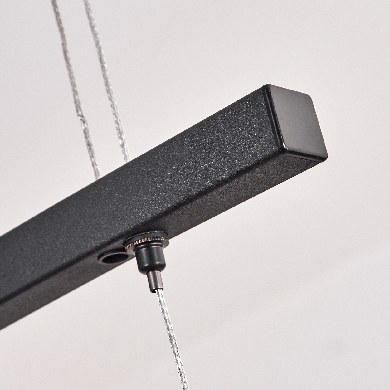 Nahaufnahme einer schwarzen Lampenaufhängung mit Metallkabeln.