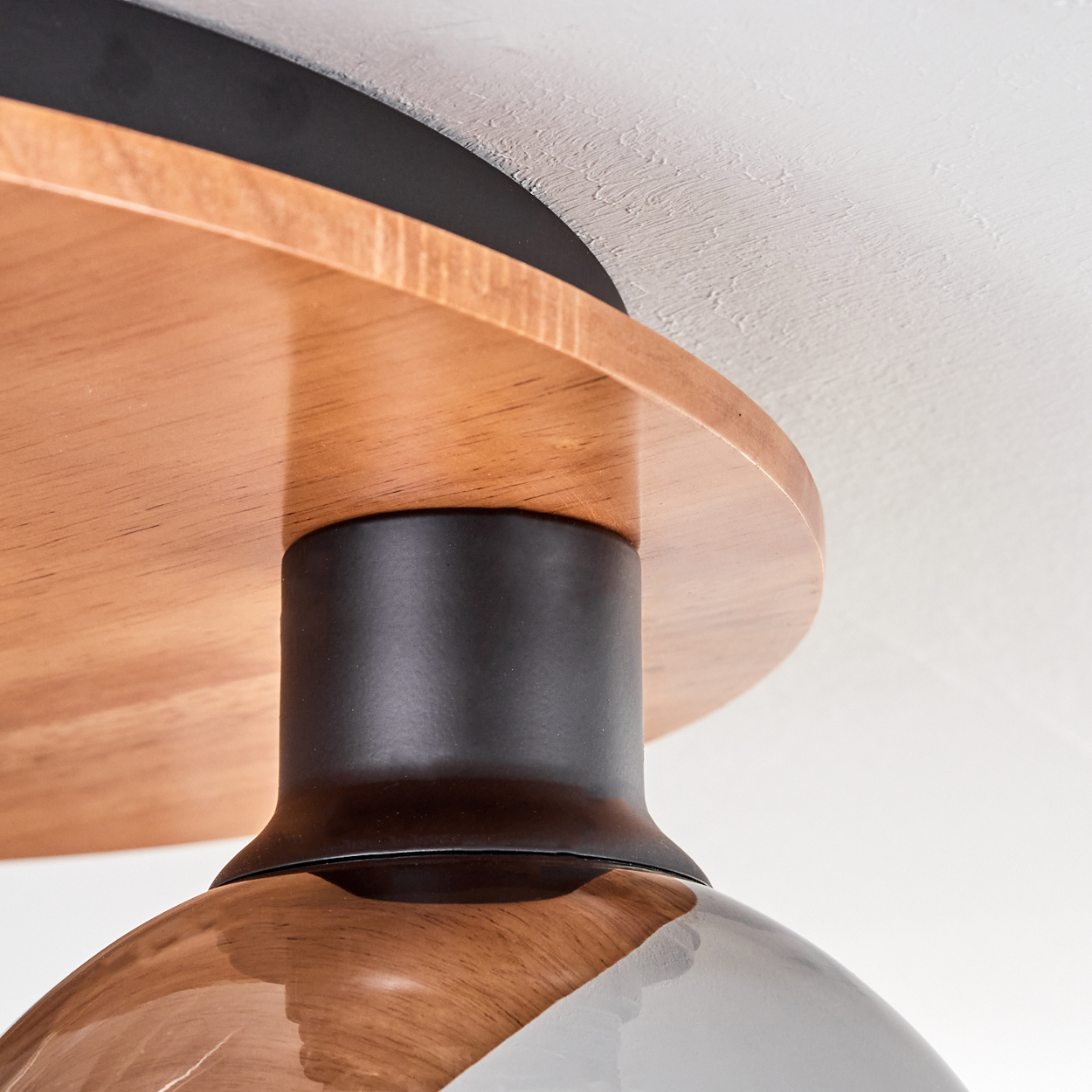 Holzdekor trifft schwarzes Metall: Detailansicht einer Lampe.