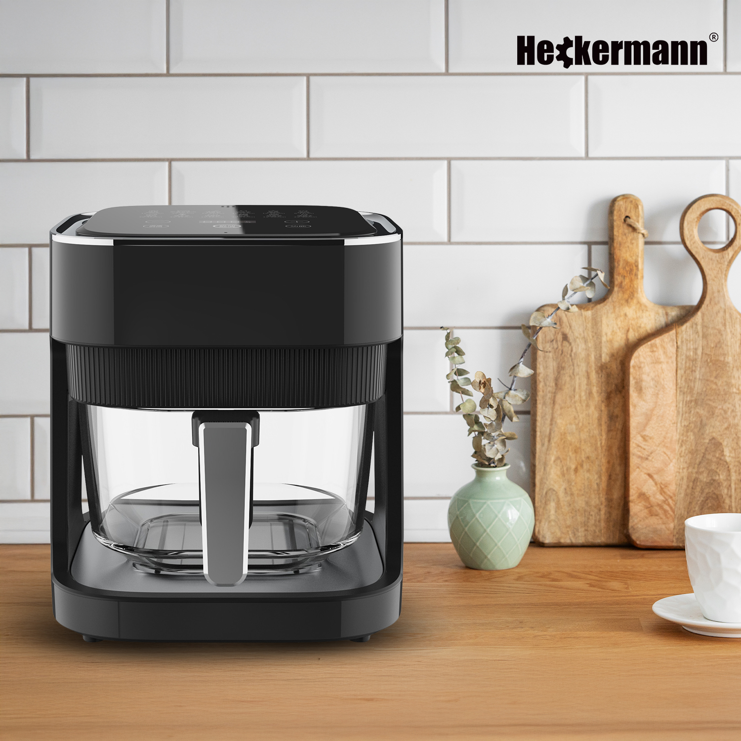 Czarna frytkownica beztłuszczowa Heckermann z przezroczystym koszem stoi na drewnianym blacie.
