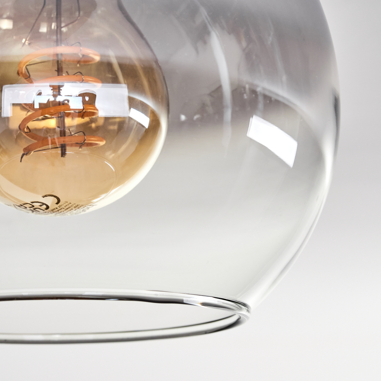 Nahaufnahme einer Glühbirne mit Spiralfilament in einem klaren Glasgehäuse.
