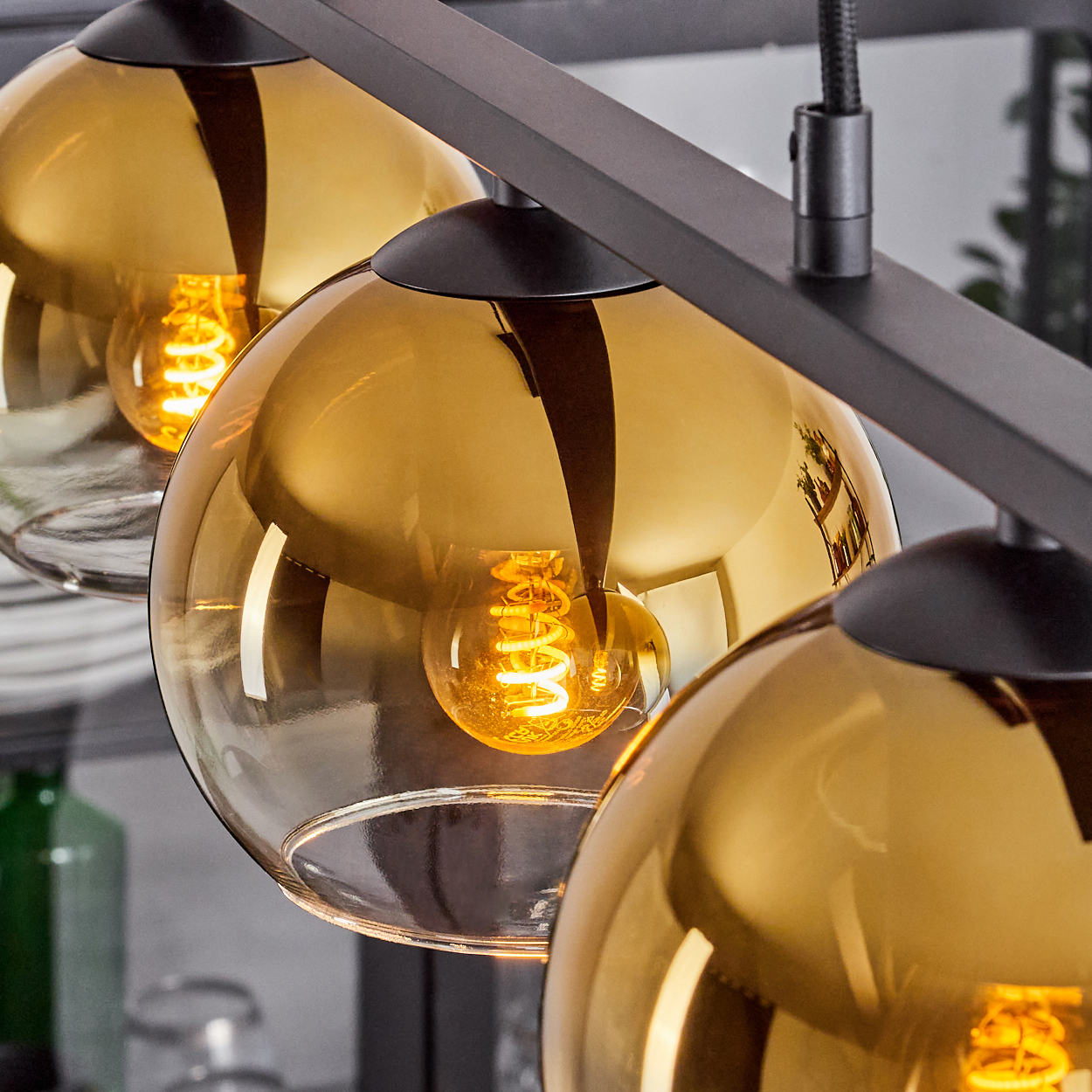 Nahaufnahme von bernsteinfarbenen Pendelleuchten mit Edison-Glühbirnen an einer schwarzen Fassung.