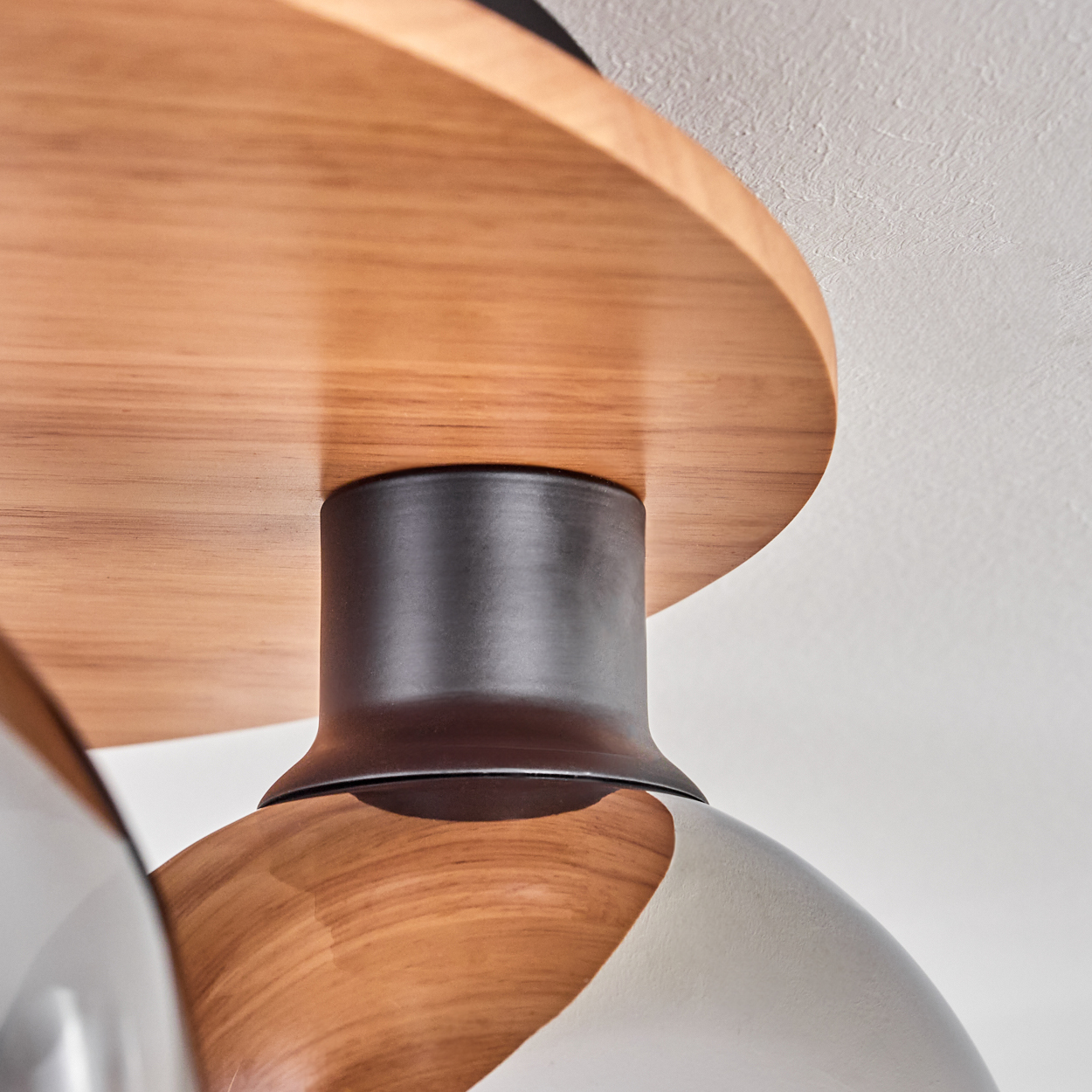 Holzplatte mit dunklem Metallzylinder und Lampenschirm.