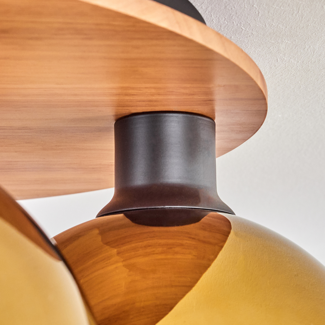 Nahaufnahme eines Lampenschirms aus bernsteinfarbenem Glas mit Holz- und Metalldetails.