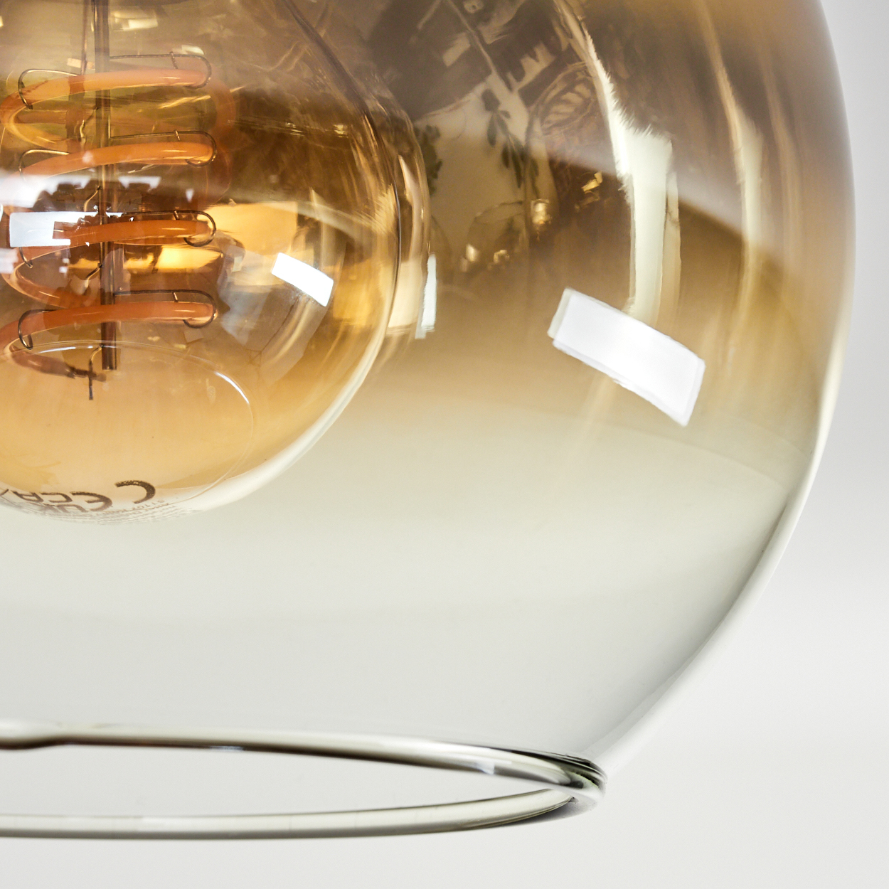 Ein bernsteinfarbener Glaskolben mit sichtbaren Spiralglühfäden und silbernem Metallring.