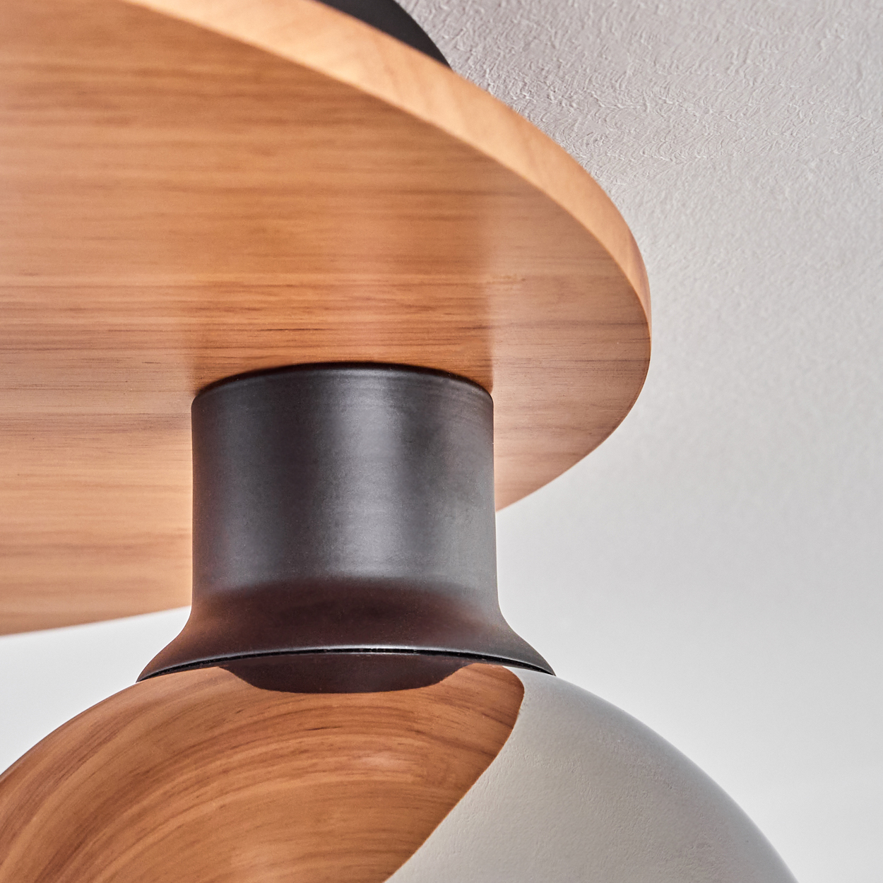 Holzdecke mit schwarzem Metallzylinder und Lampenschirm.