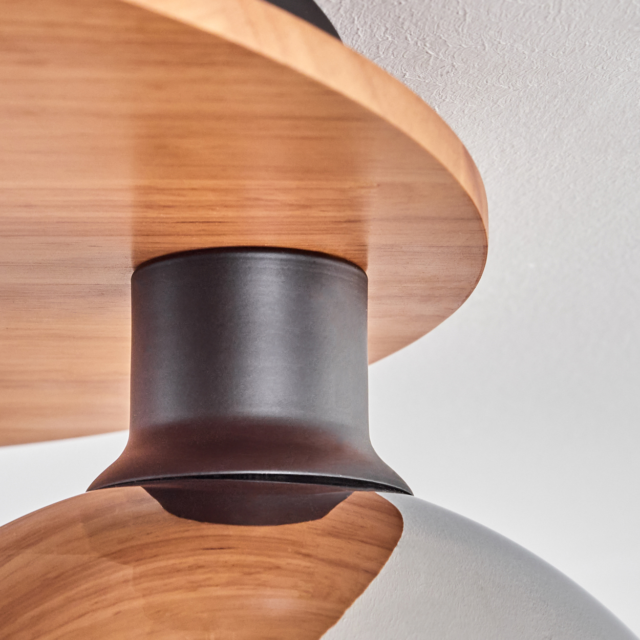 Holzdekor trifft auf dunklen Metallzylinder, der zu einer Kuppel übergeht.