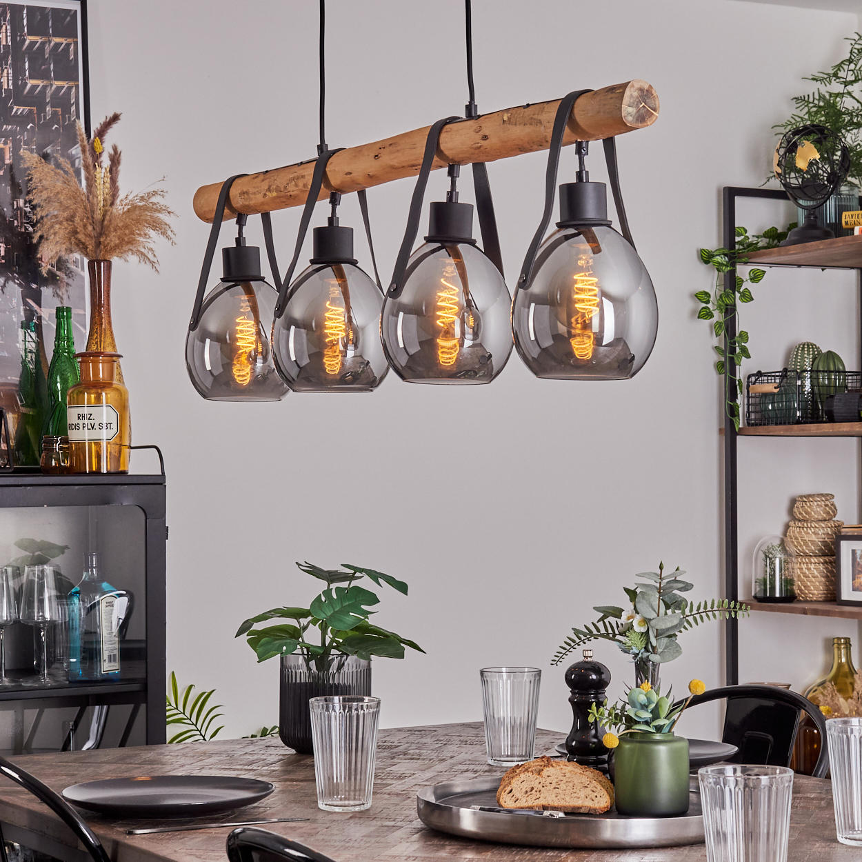 Hängelampe mit Holz und Leder über einem Holztisch mit Gläsern.