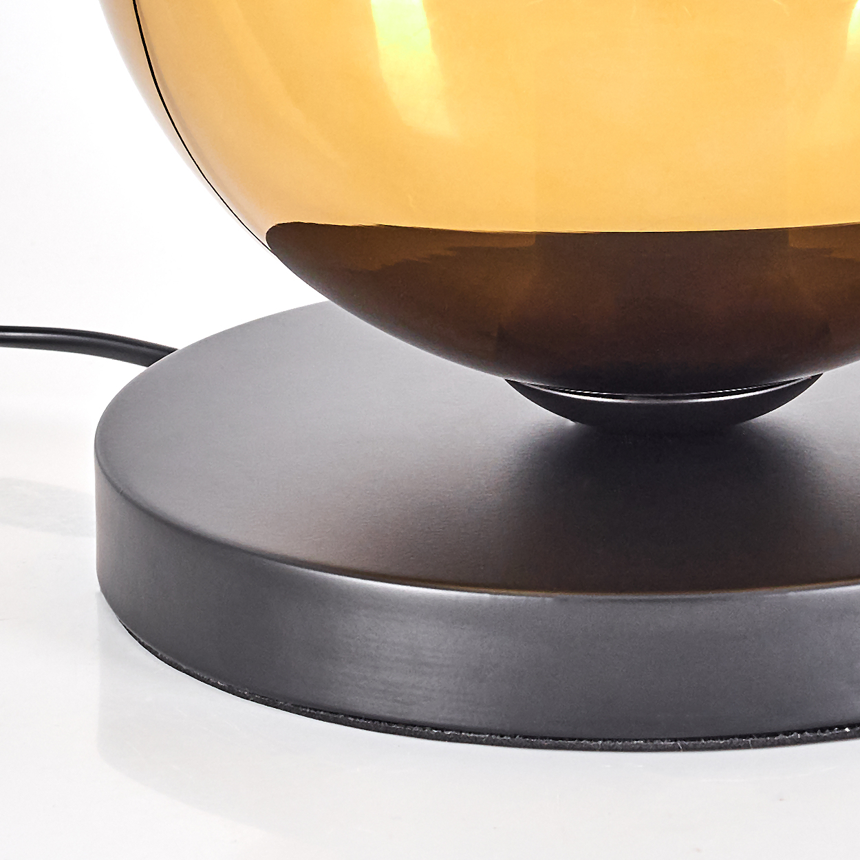 Nahaufnahme einer Lampe mit goldenem Lampenschirm und dunklem Sockel.