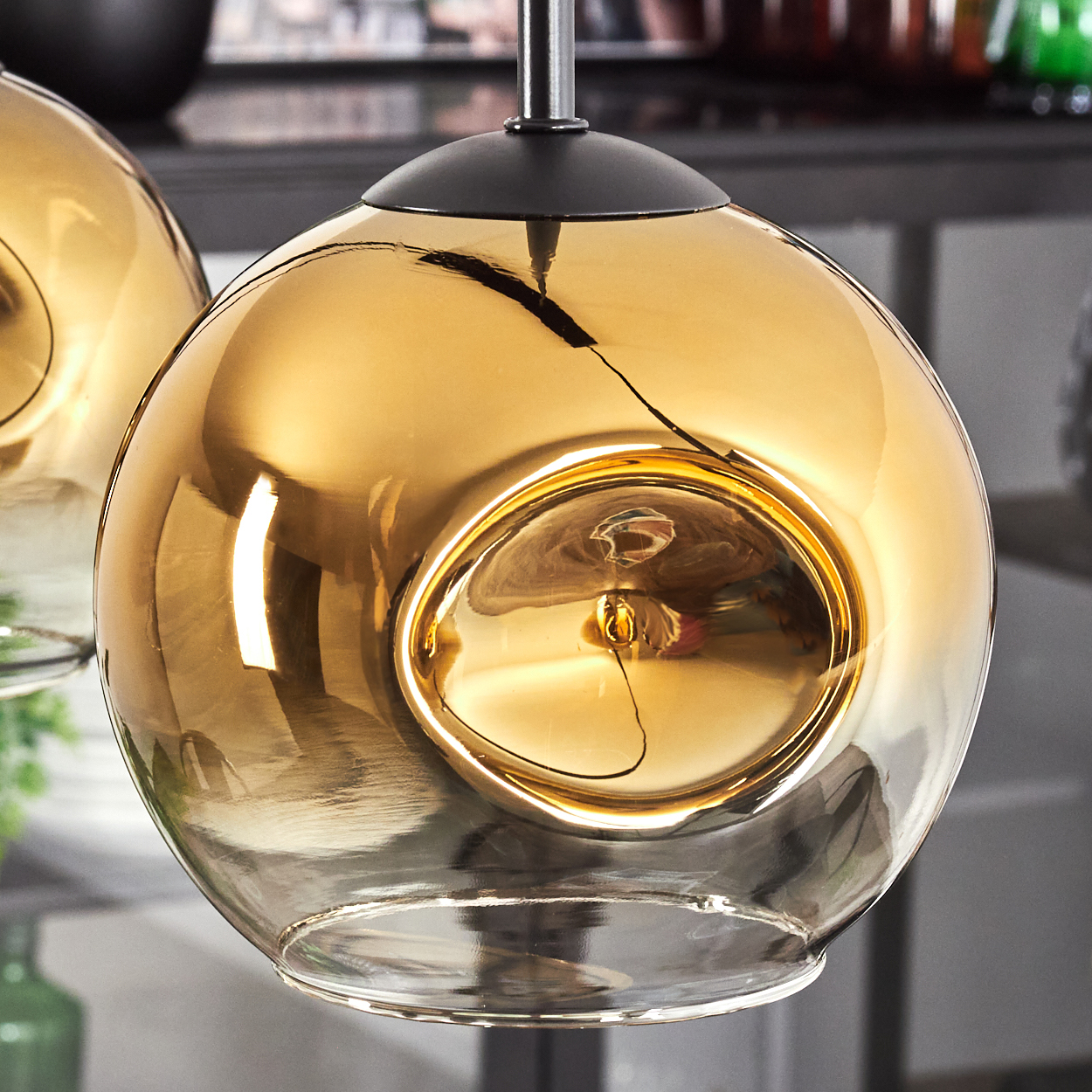 Eine bernsteinfarbene Glaskugel-Pendelleuchte mit schwarzer Metallhalterung.