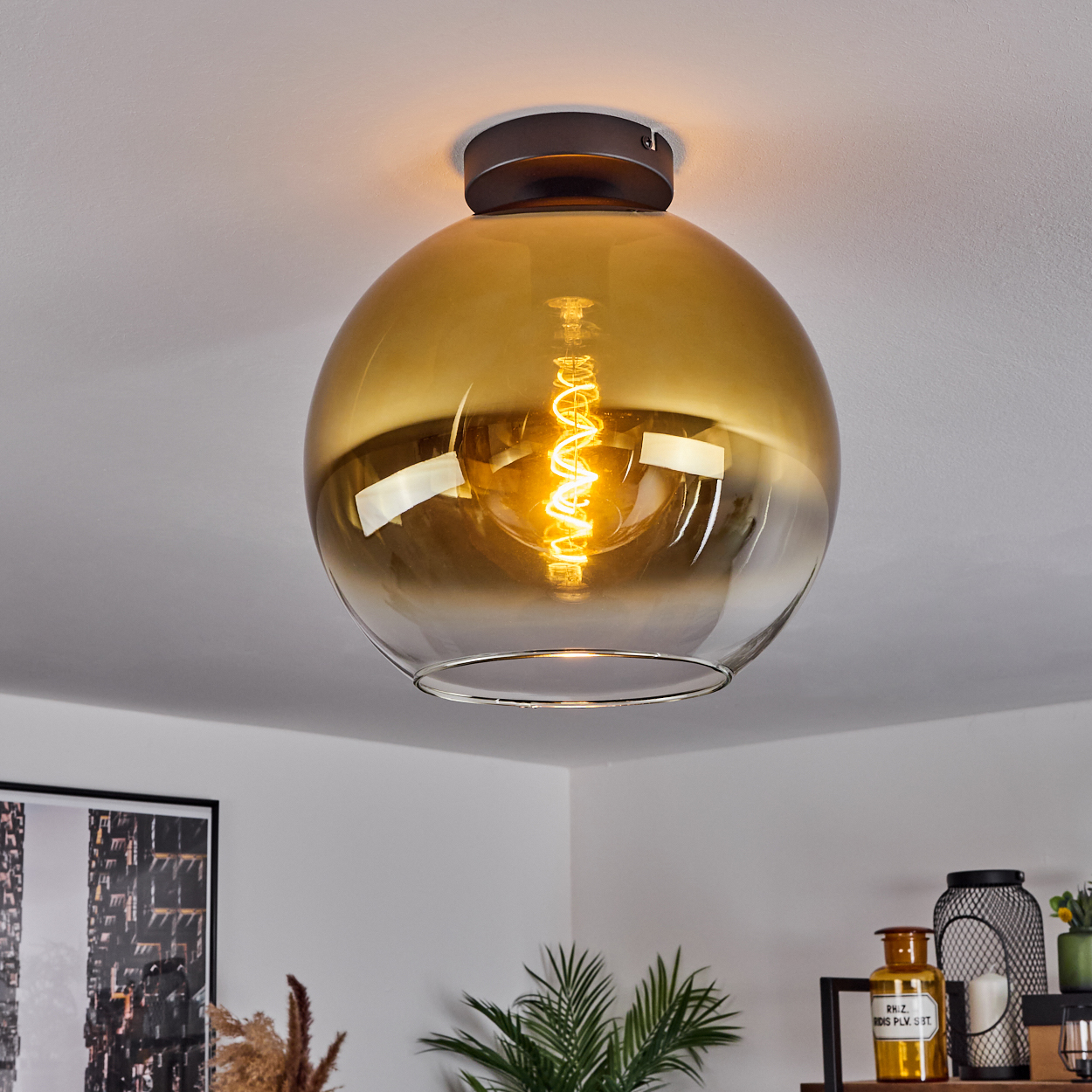 Eine bernsteinfarbene Glaskugel-Deckenleuchte mit einer Spiralglühbirne.