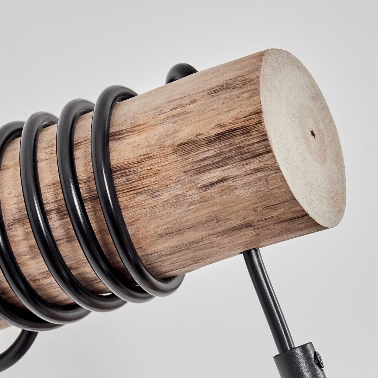 Ein Holzstamm mit schwarzen Metallspiralen und Ständer auf weißem Hintergrund.