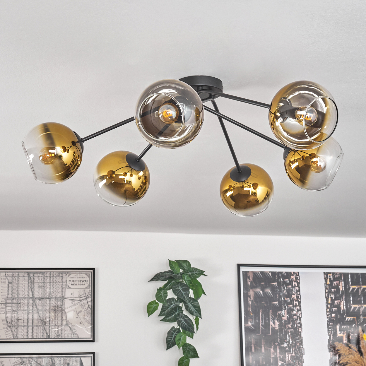Eine Deckenleuchte mit sechs Armen und Glaskugeln in Gold und Rauchglas.