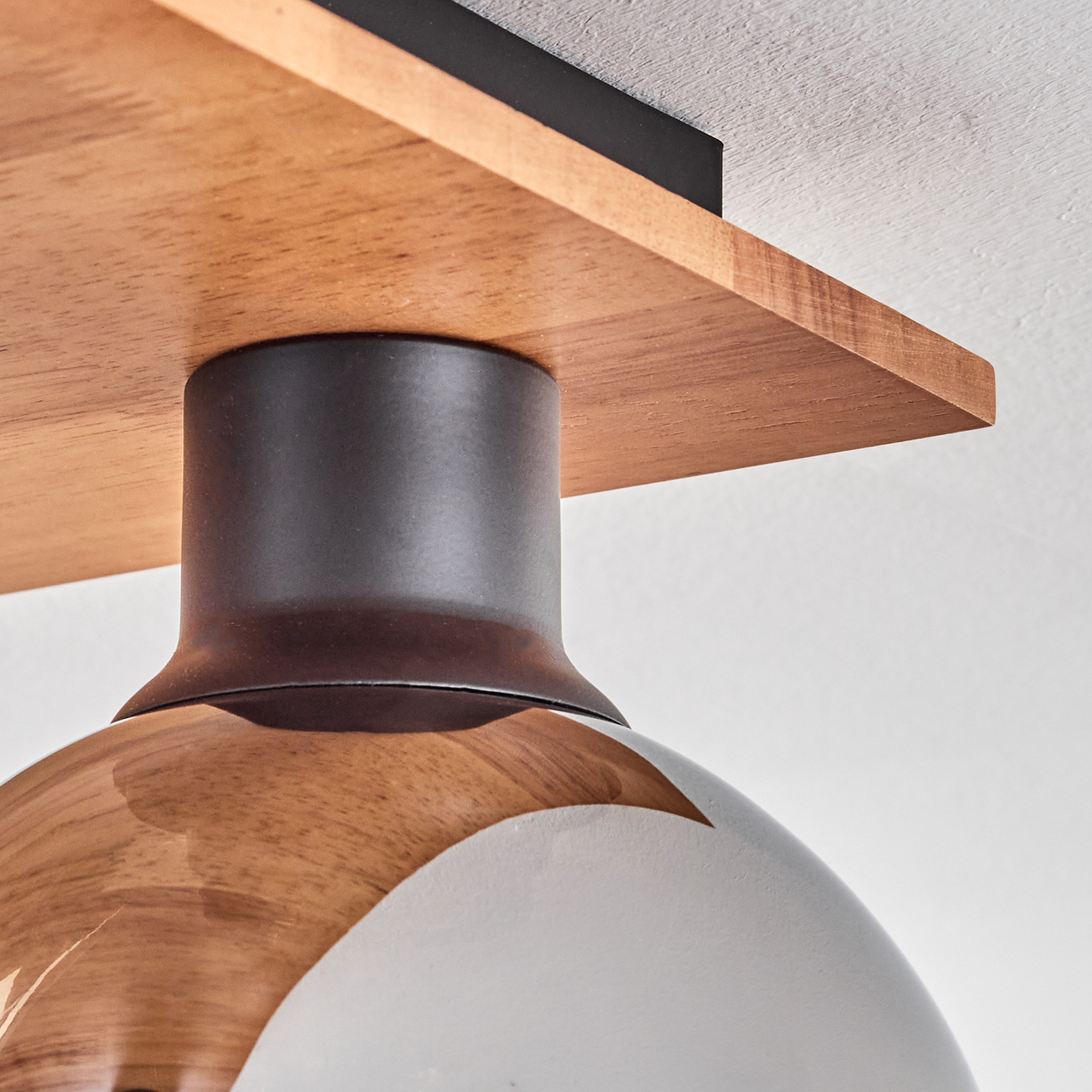 Deckenleuchte mit Holzplatte, dunklem Metall und Glaslampenschirm.