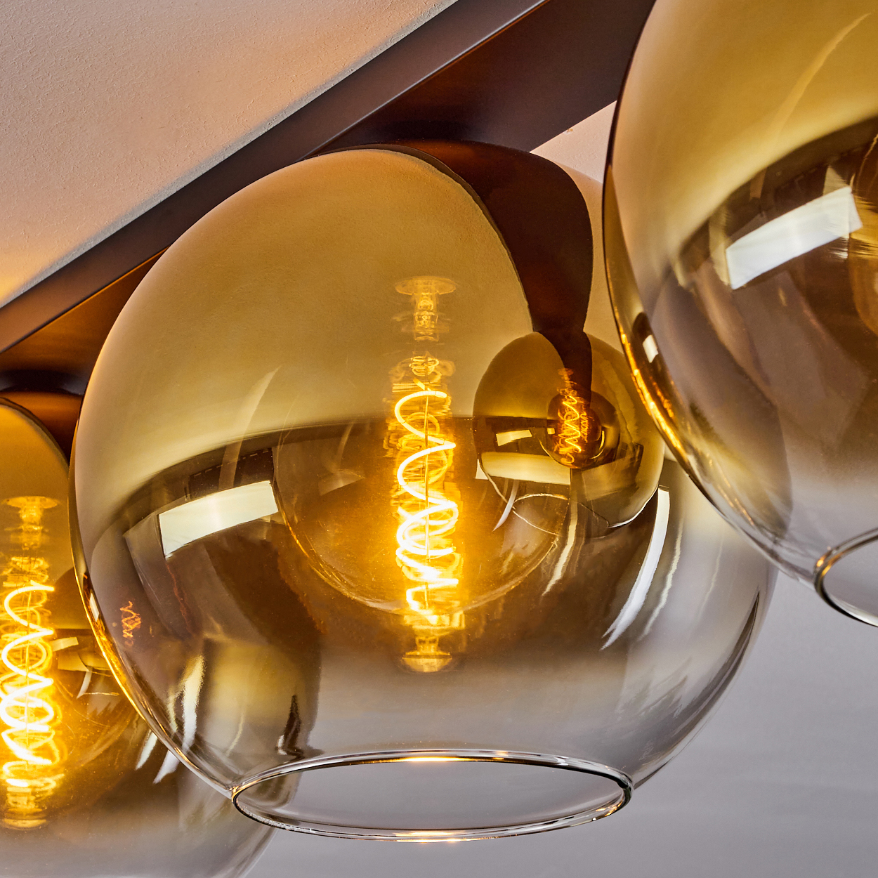 Nahaufnahme einer modernen Lampe mit bernsteinfarbenen Glaskugeln und Glühfadenlampen.