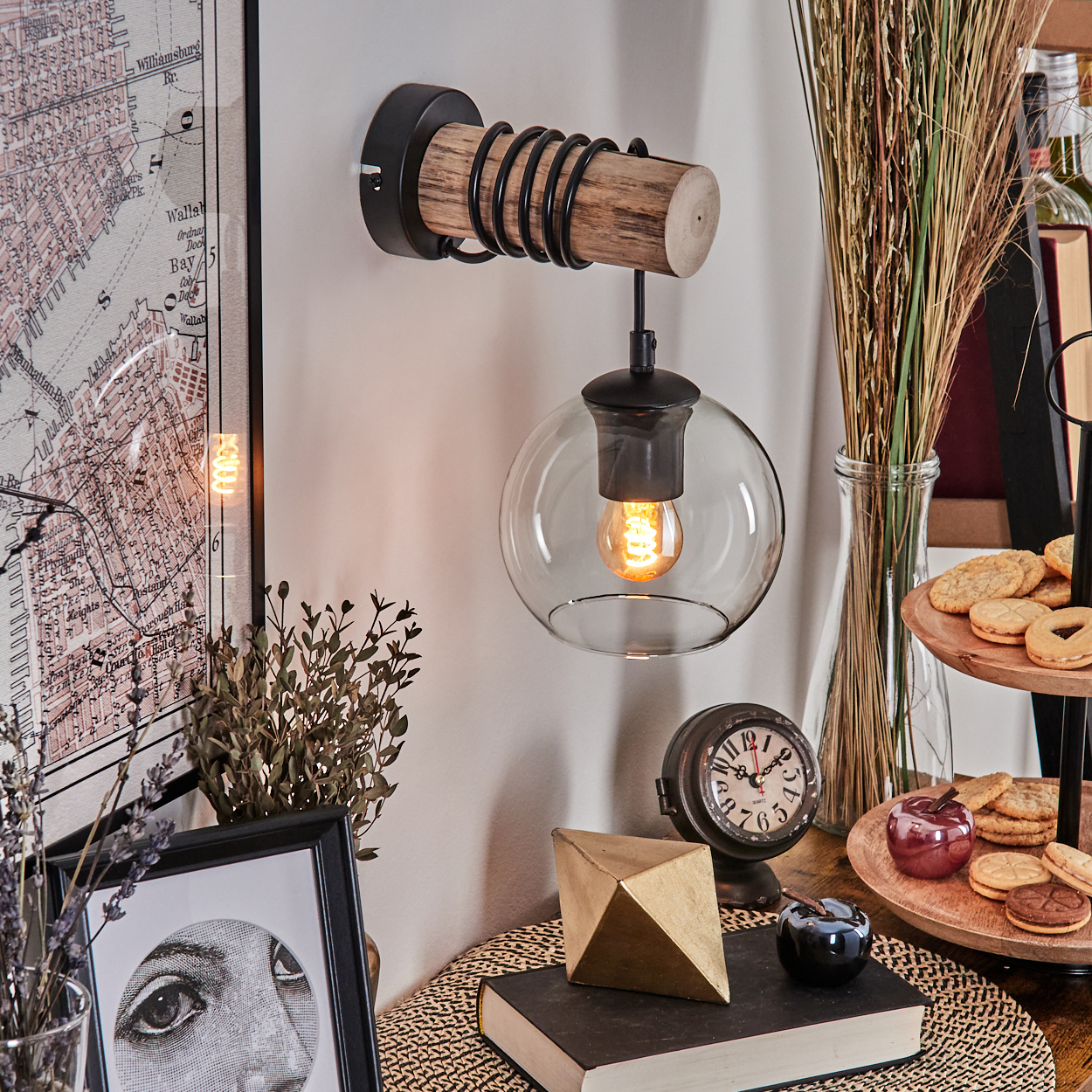 Wandleuchte mit Holz, Metall und Glas, daneben eine Karte und Deko.