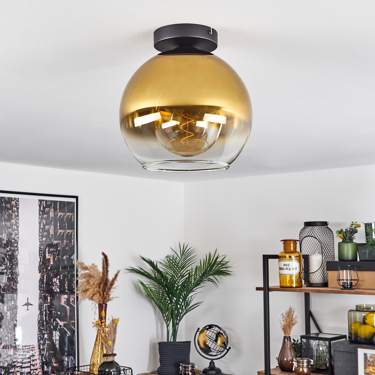 Eine goldene Glaslampe hängt von der Decke, mit einer Glühbirne im Inneren.