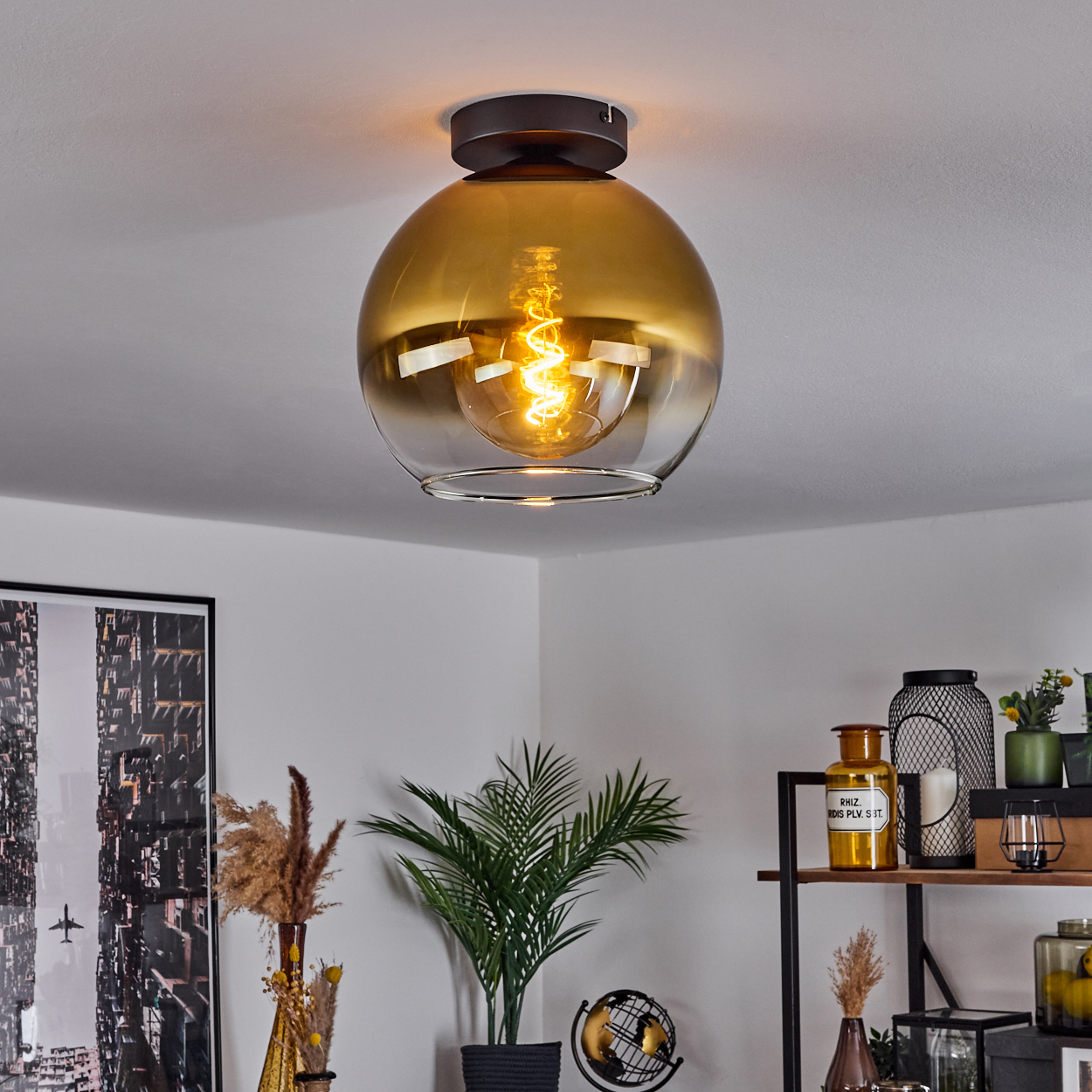 Eine bernsteinfarbene Glaslampe mit Glühfaden hängt an der Decke.