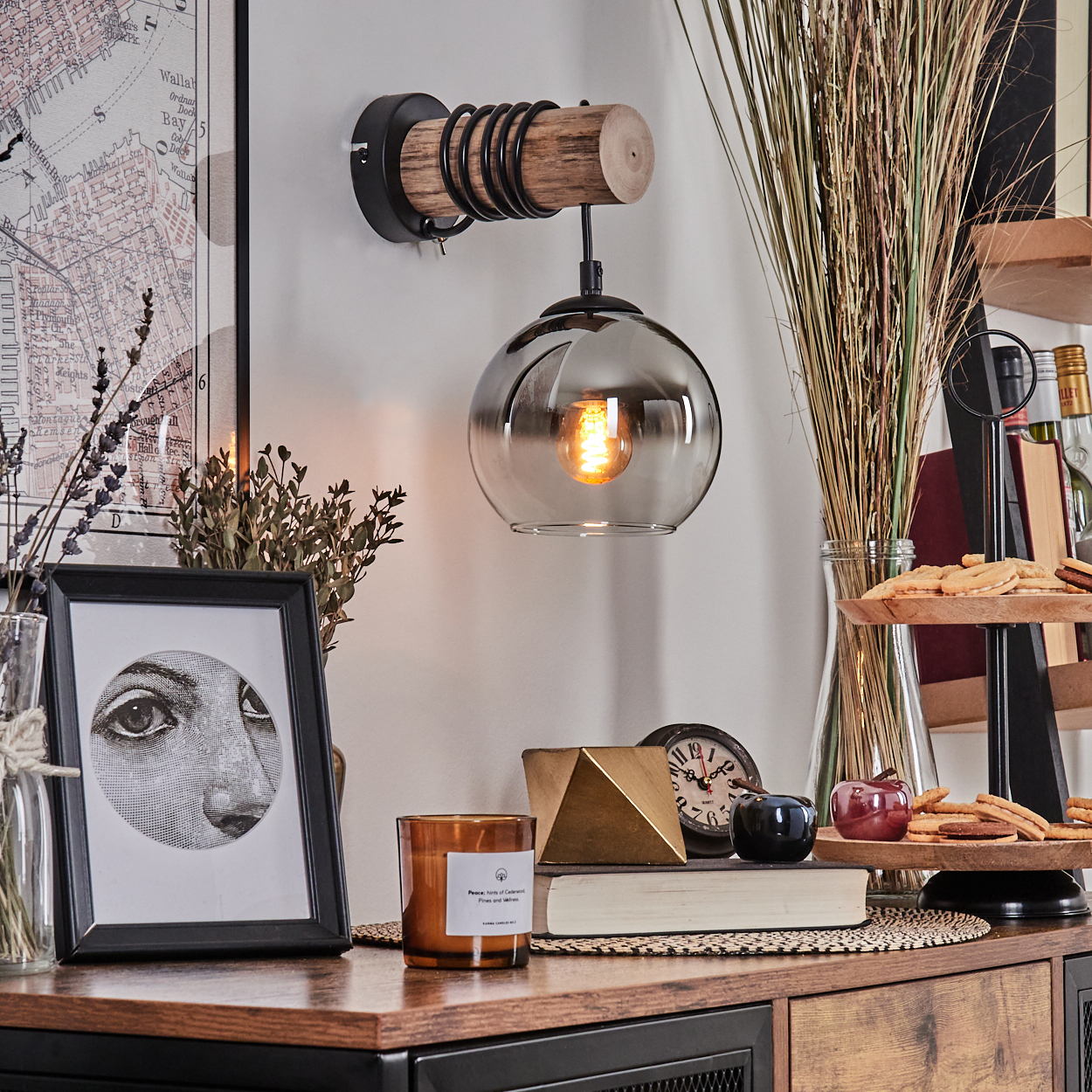 Ein Wandleuchter mit Holz und Metall über einem Schrank mit Deko.