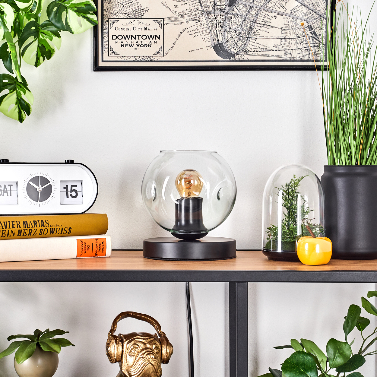 Ein Bücherregal mit Deko: Lampe, Bücher, Pflanzen und eine New Yorker Karte.