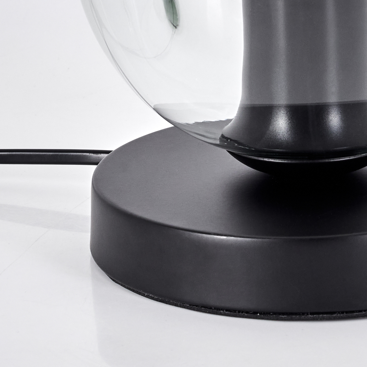 Nahaufnahme einer Lampe mit schwarzem Sockel und Glaskuppel.