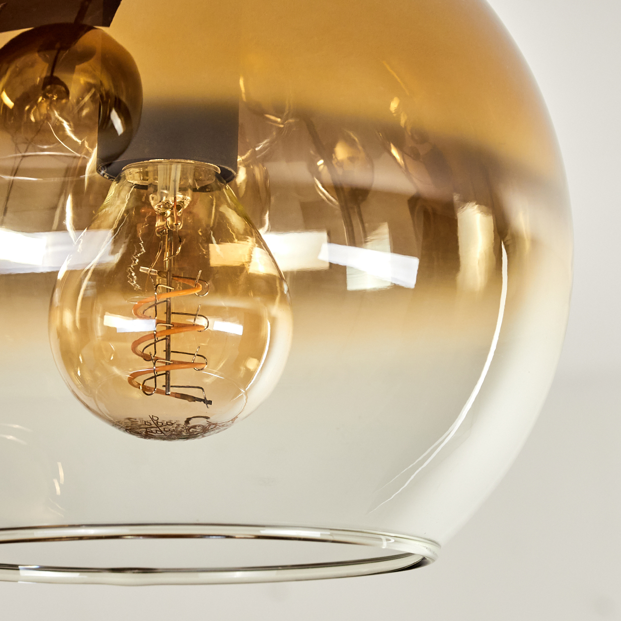 Eine Nahaufnahme einer Glühbirne mit einem spiralförmigen Glühfaden in einem bernsteinfarbenen Glas.